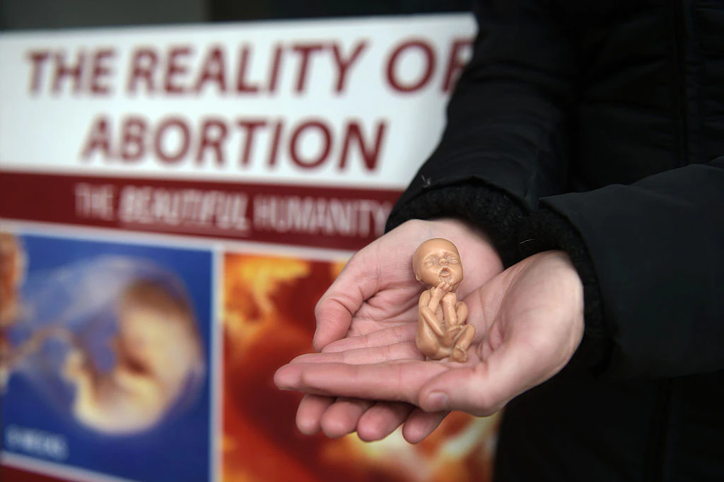 BELFAST, NORTHERN IRELAND - APRIL 07: A Pro Life campaigner displays a plastic doll representing a 12 week old foetus as she stands outside the Marie Stopes Clinic on April 7, 2016 in Belfast, Northern Ireland. The anit abortion supporters have protested outside the clinic where women can go for advice concerning terminating their pregnancy since it opened in 2012. The abortion laws in Northern Ireland are in the news again after a 21 year old Northern Irish woman was convicted and sentenced earlier this week for procuring a miscarriage. The woman who cannot be named for legal reasons had pleaded guilty to two charges of procuring her own abortion by using a poison and of supplying a poison with intent to procure a miscarriage, she was ten-twelve weeks pregnant at the time. She was given a three-month prison sentence by Judge David McFarland at Belfast high court, which was suspended for two years. Unlike the rest of the United Kingdom, the law in Northern Ireland rules that terminating a pregnancy is illegal except in very limited circumstances.