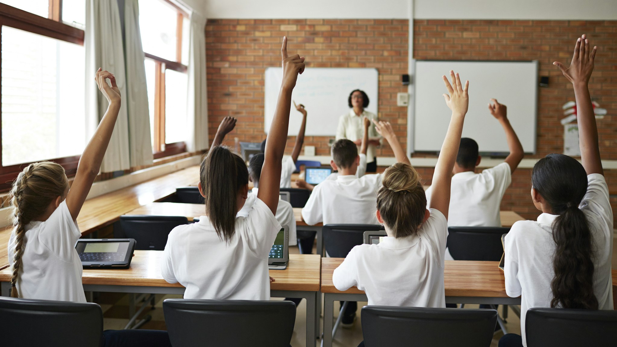 Back view of schoolclass with raised hands - stock photo