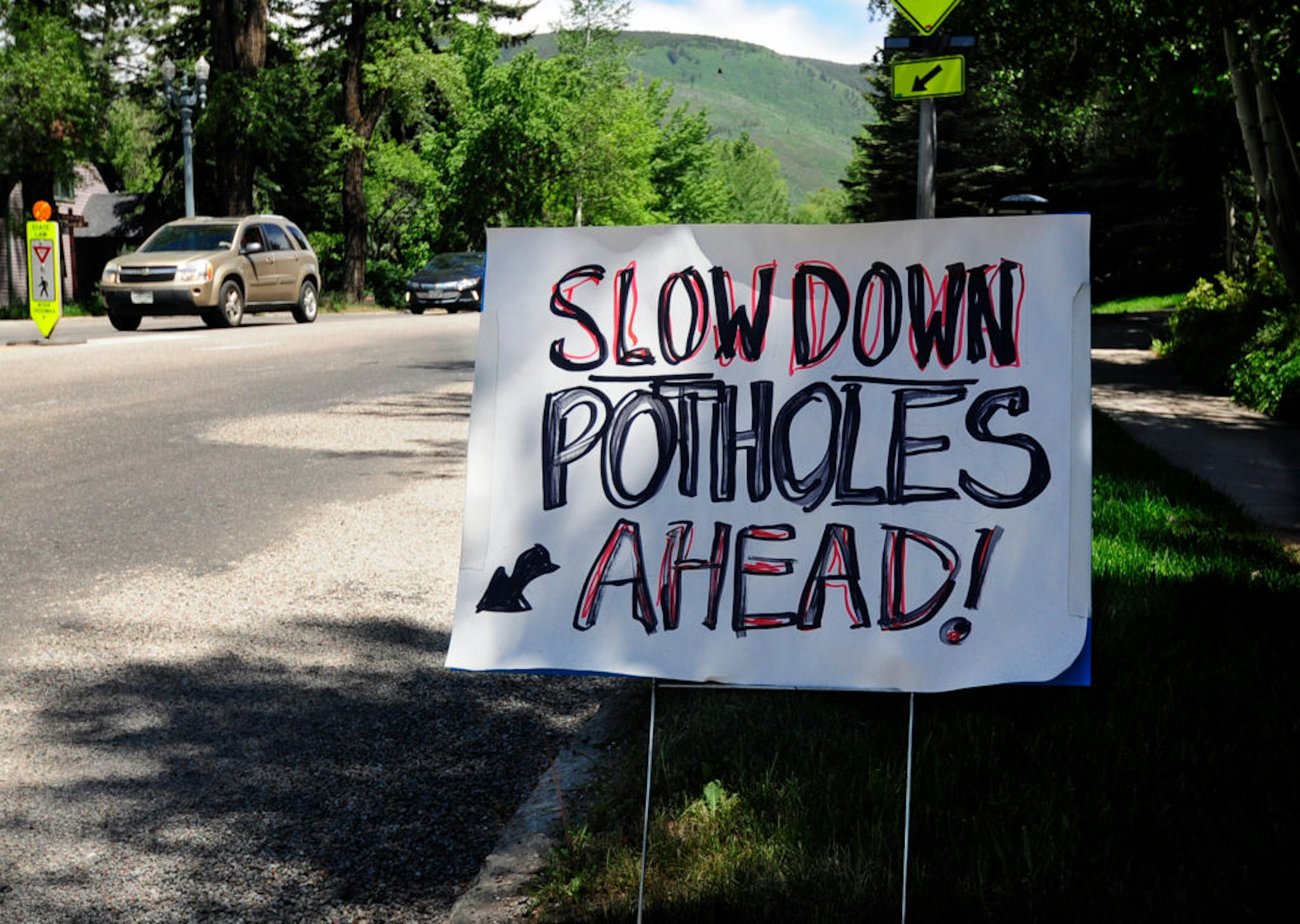 ASPEN, CO - JUNE 11, 2017: A hand-lettered, homemade sign posted beside an Aspen, Colorado, street warns motorists that there are pot holes ahead.