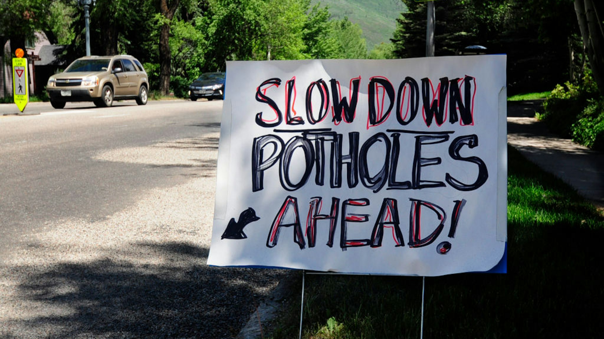 ASPEN, CO - JUNE 11, 2017: A hand-lettered, homemade sign posted beside an Aspen, Colorado, street warns motorists that there are pot holes ahead.