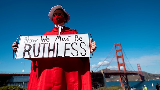 A woman dressed as a character from The Handmaid's Tale holds up a sign in homage to the late Supreme Court Justice Ruth Bader Ginsberg during a celebration march for president-elect Joe Biden at the Golden Gate Bridge in San Francisco, California on November 07, 2020. - Democrat Joe Biden has won the White House, US media said November 7, defeating Donald Trump and ending a presidency that convulsed American politics, shocked the world and left the United States more divided than at any time in decades.