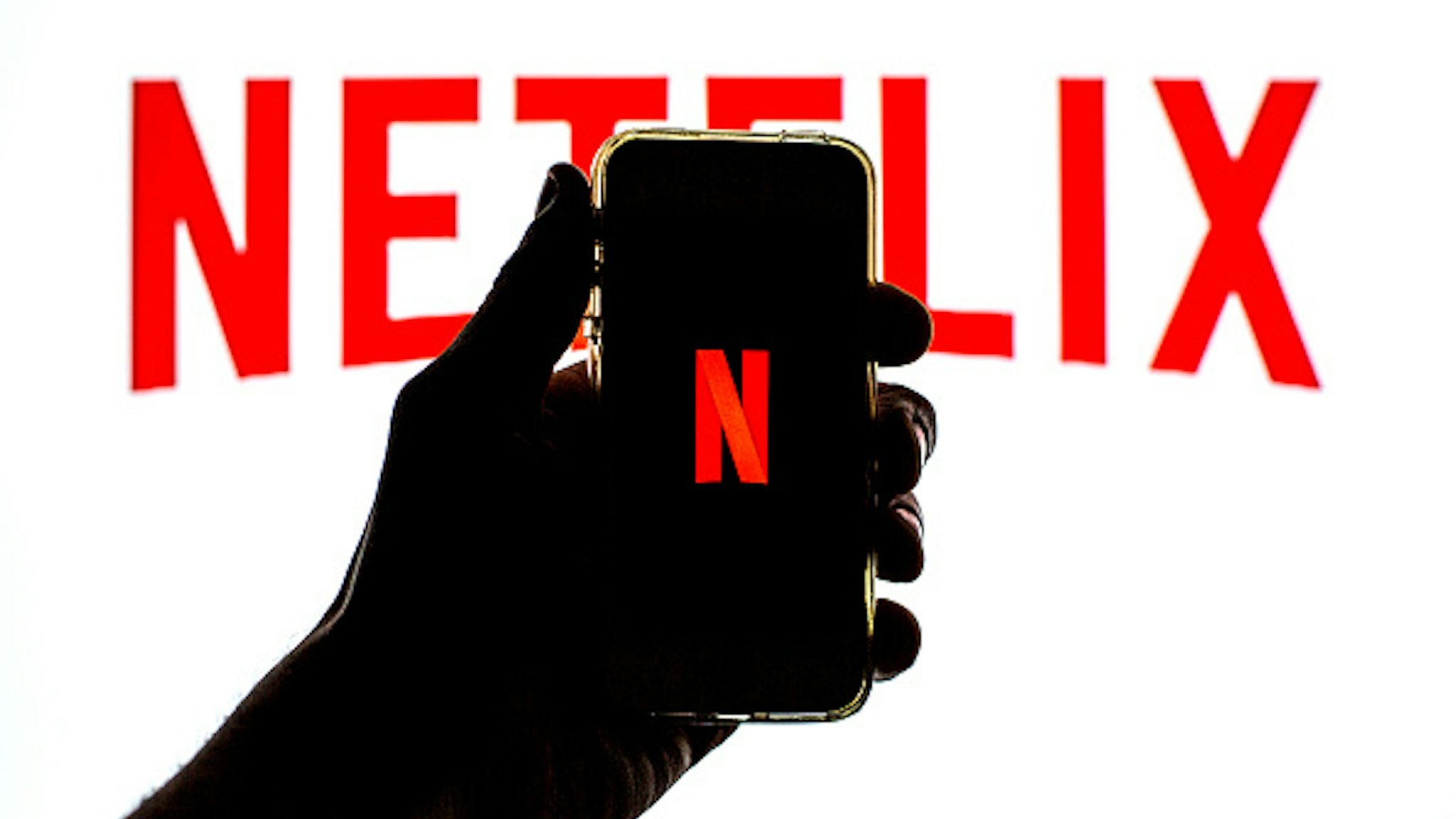 SPAIN - 2021/03/23: In this photo illustration the Netflix App seen displayed on a smartphone screen with the Netflix logo in the background.