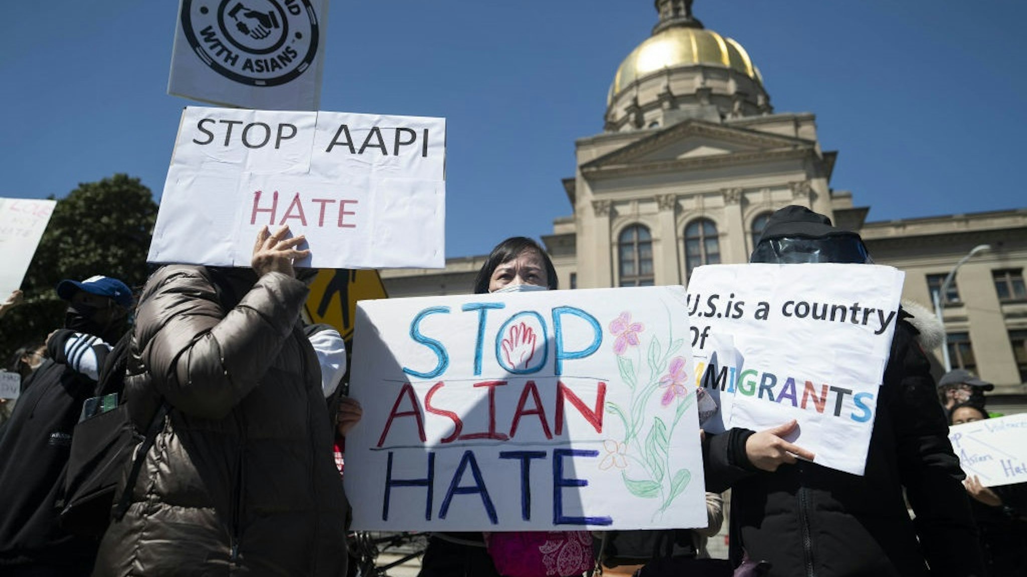 Demonstrators hold signs during a Stop AAPI Hate Rally outside the State Capitol building in Atlanta, Georgia, U.S., on Saturday, March 20, 2021.