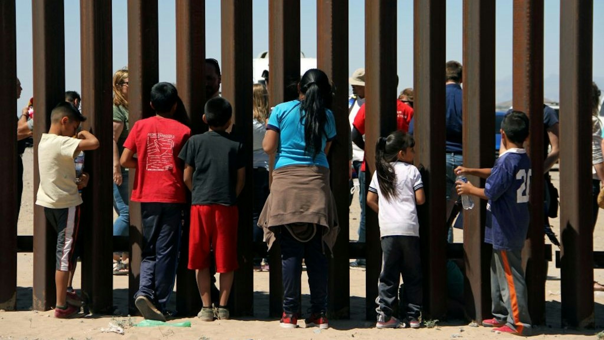 Children from the Anapra area observe a binational prayer performed by a group of religious presbyters on the border wall between Ciudad Juarez, Chihuahua state, Mexico and Sunland Park, New Mexico, US, on May 3, 2018. (Photo by Herika Martinez / AFP) (Photo credit should read