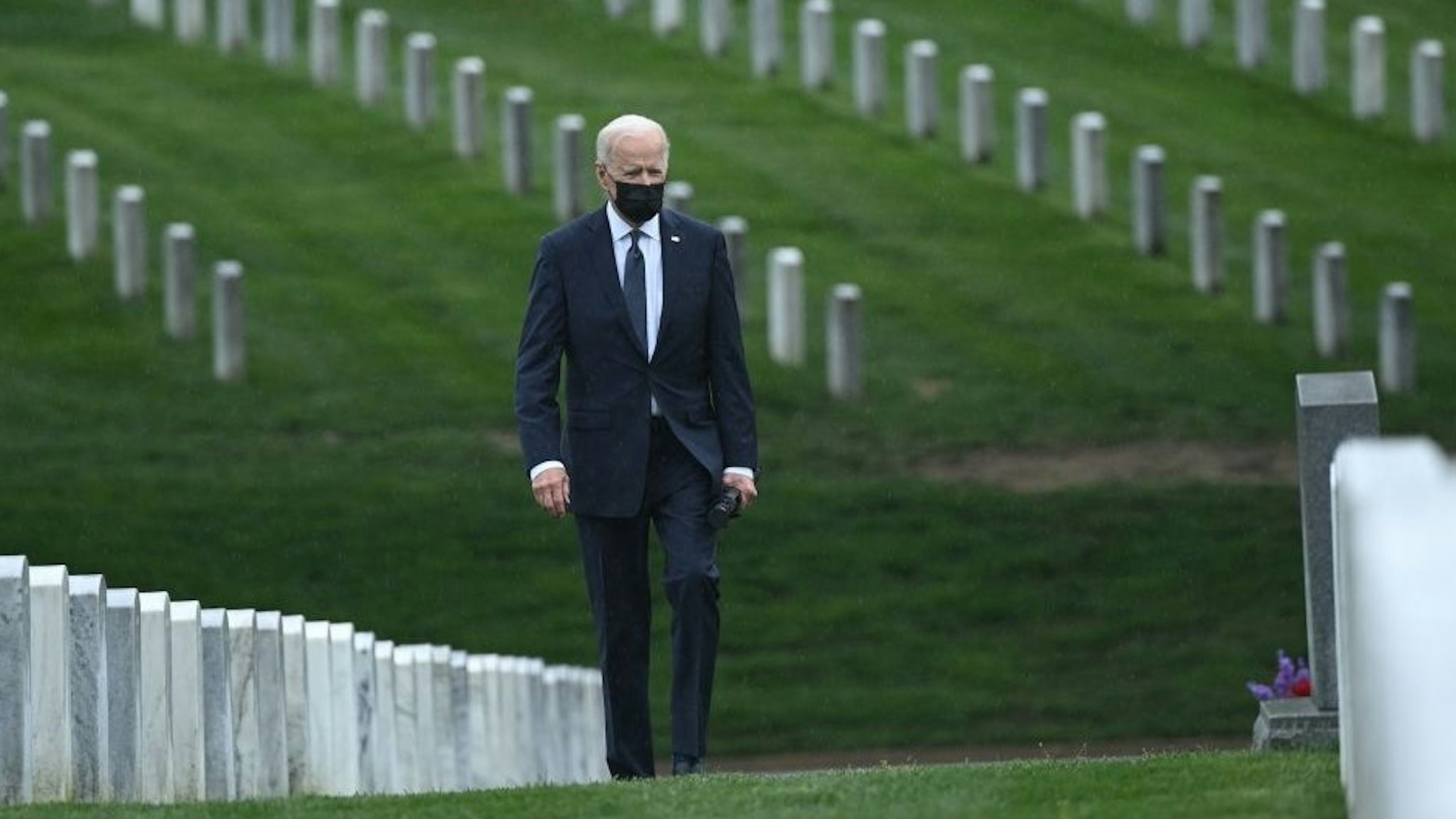 US President Joe Biden walks through Arlington National cemetary to honor fallen veterans of Afghan conflict in Arlington, Virginia on April 14, 2021. - President Joe Biden announced it's "time to end" America's longest war with the unconditional withdrawal of troops from Afghanistan, where they have spent two decades in a bloody, largely fruitless battle against the Taliban. (Photo by Brendan SMIALOWSKI / AFP) (Photo by