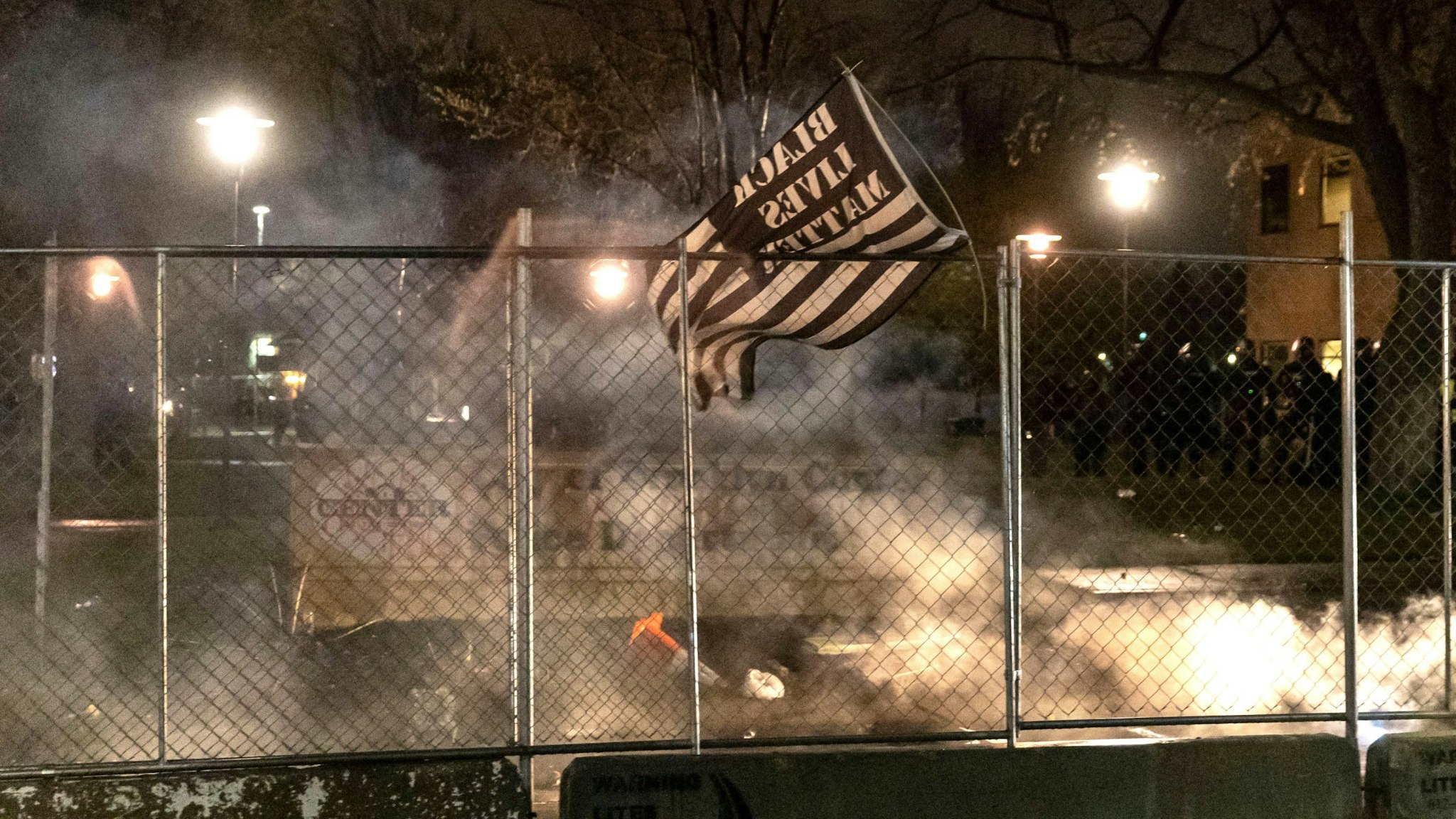 A Black Lives Matter flag is seen after curfew as demonstrators protest the death of Daunte Wright who was shot and killed by a police officer in Brooklyn Center, Minnesota on April 12, 2021. - A suburb of Minneapolis was under curfew early April 12, 2021 after US police fatally shot a young Black man, sparking protests not far from where a former police officer was on trial for the murder of George Floyd.Hundreds of people gathered outside the police station in Brooklyn Center, northwest of Minneapolis, with police later firing teargas and flash bangs to disperse the crowd, according to an AFP videojournalist.