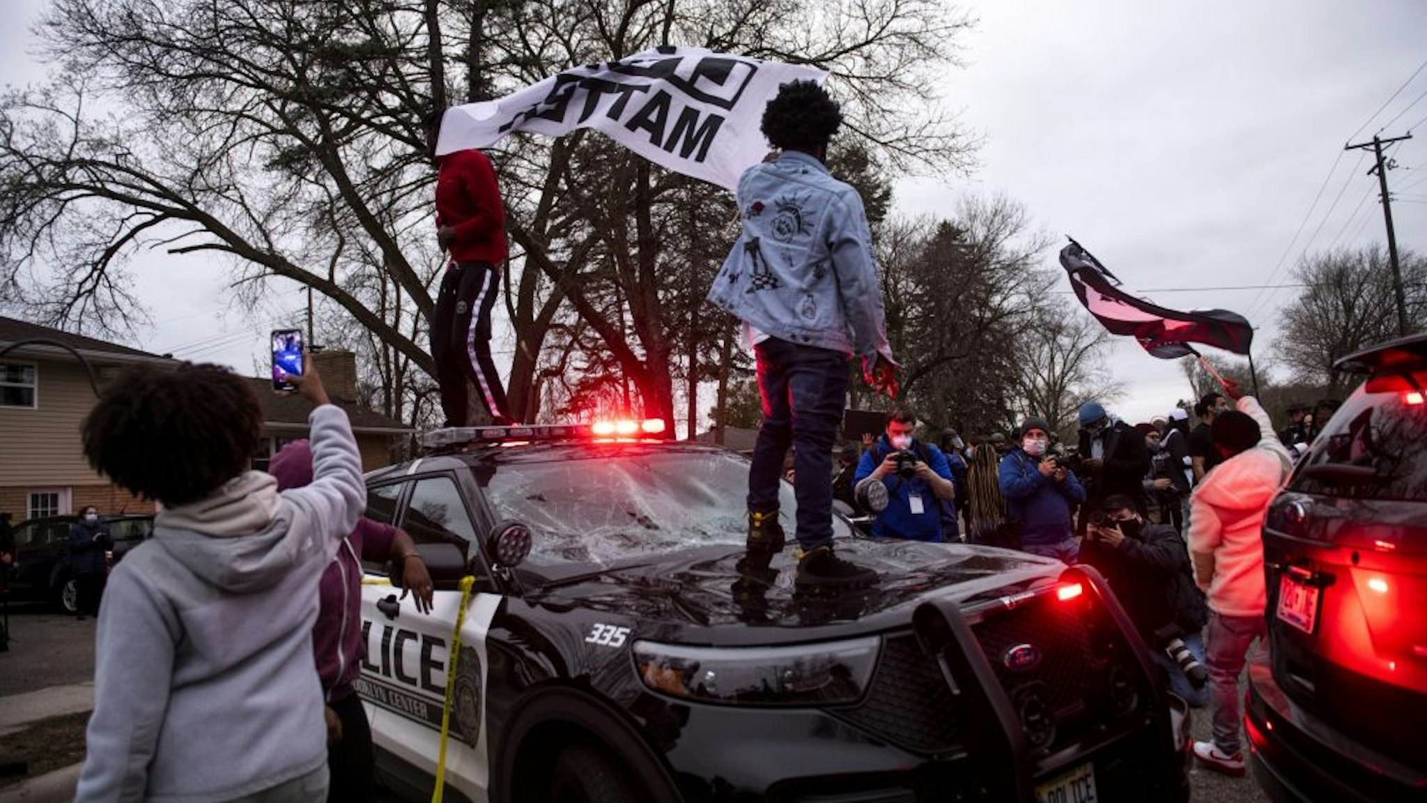 BROOKLYN CENTER, MN - APRIL 11: People stand on a police cruiser as protesters take to the streets after Brooklyn Center police shot and killed Daunte Wright during a traffic stop on April 11, 2021 in Brooklyn Center, Minnesota. A crowd gathered to confront police as they held a line while investigators searched the scene.