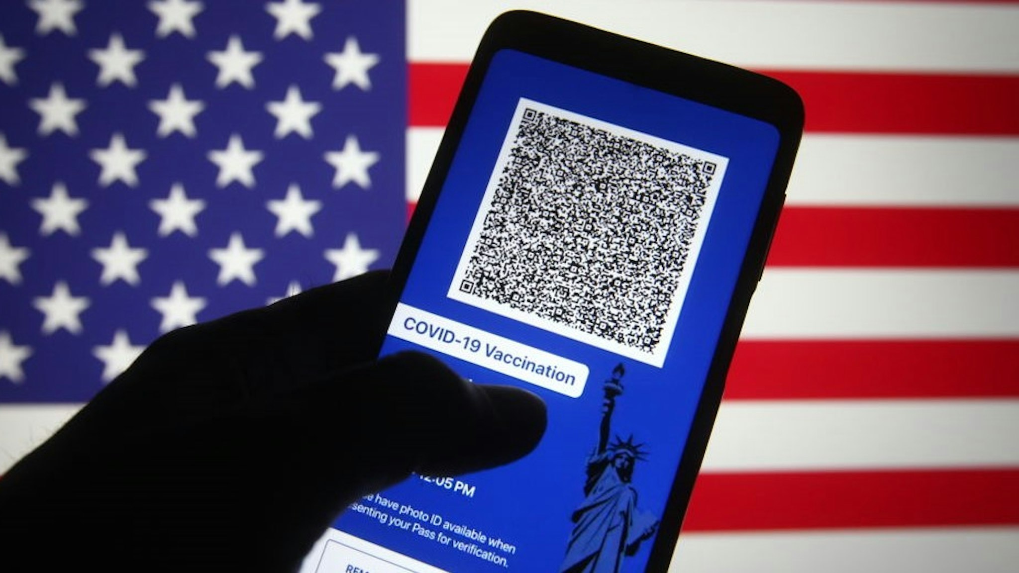 UKRAINE - 2021/03/28: In this photo illustration, Excelsior Pass app which provides digital proof of COVID-19 vaccination or negative test results seen displayed on a smartphone screen in front of the US flag. The first COVID-19 vaccine passports' in the US called the Excelsior Pass was launched on Friday in New York, reportedly by the media on 27 March. Excelsior Pass provides digital proof of COVID-19 vaccination or negative test results of three types of passes: COVID-19 Vaccination Pass, COVID-19 PCR Test Pass, and COVID-19 Antigen Test Pass. (Photo Illustration by
