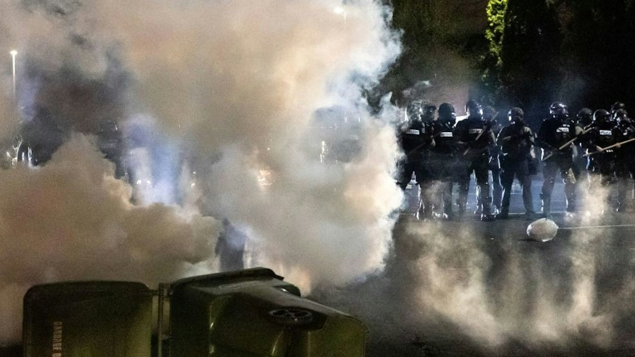 Police officers in riot gear fire tear gas in front of the Brooklyn Center Police Station as people gather to protest after a police officer shot and killed a black man in Brooklyn Center, Minneapolis, Minnesota on April 11, 2021. - Protests broke out April 11, 2021 night after US police fatally shot a young Black man in a suburb of Minneapolis -- where a former police officer is currently on trial for the murder of George Floyd. Hundreds of people gathered outside the police station in Brooklyn Center, northwest of Minneapolis. Police fired teargas and flash bangs at the demonstrators, according to an AFP videojournalist at the scene. (Photo by Kerem Yucel / AFP) (Photo by