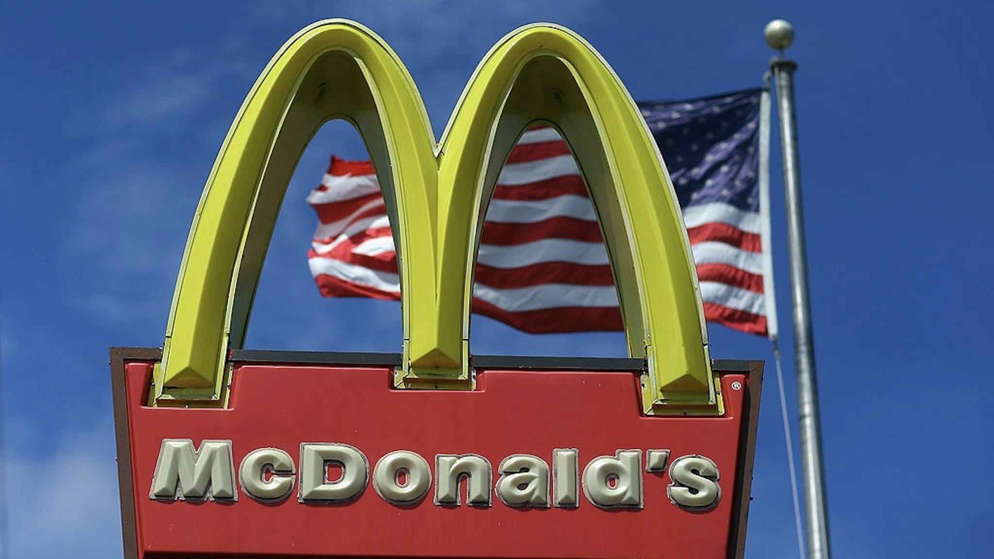 McDonalds Q2 Profit Drops 4.5 Percent On Stronger Dollar, Tougher Competition MIAMI, FL - JULY 23: A sign for a McDonald's restaurant sits in front of an American Flag July 23, 2012 in Miami, Florida. The company announced that 2nd quarter profit dropped 4.5 percent. (Photo by Joe Raedle/Getty Images)