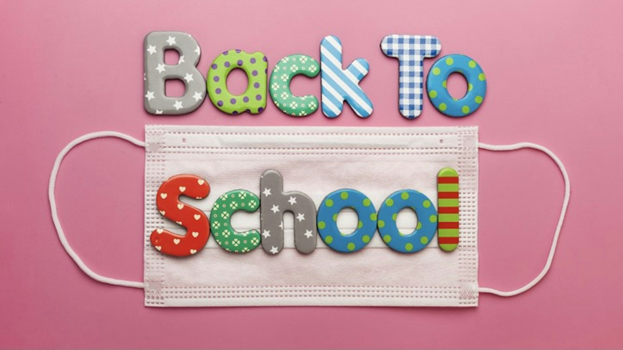 Colourful Back To School Concept Top View - stock photo Covid-19 facemask featuring colourful children's letters in a conceptual top view shot Photography by Andrew Katsaitis via Getty Images