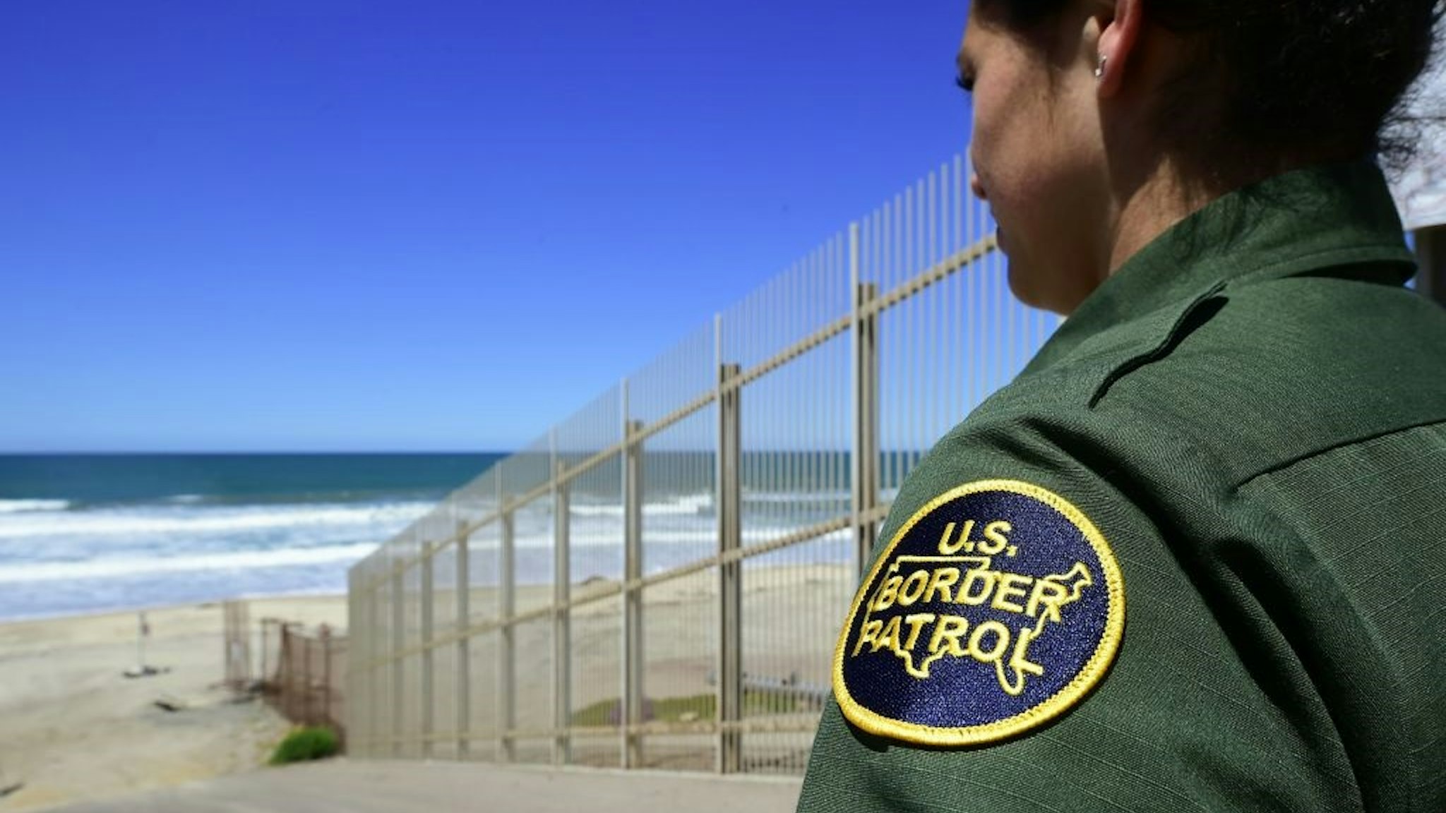 A US Customs and Border Protection agent looks toward the ocean from within the Border Infrastructure System, a no man's land area between the wall and fence which runs for 14 miles inland from the Pacific Ocean separating California from Mexico on April 17, 2018 in San Diego, California across from La Playa, Mexico a day after California rejected plans by the federal government for National Guard troops on the border.