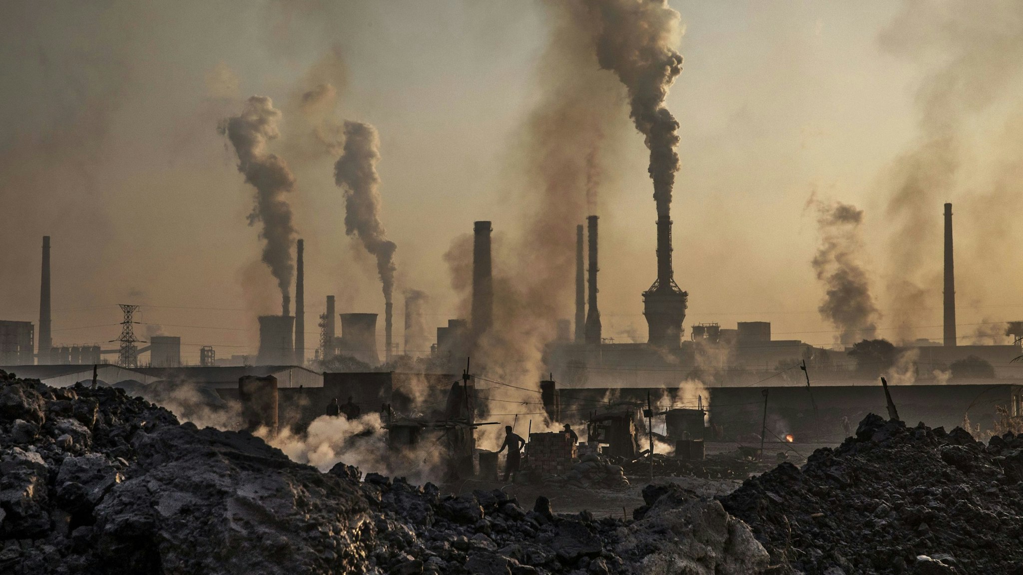 INNER MONGOLIA, CHINA - NOVEMBER 04: Smoke billows from a large steel plant as a Chinese labourer works at an unauthorized steel factory, foreground, on November 4, 2016 in Inner Mongolia, China. To meet China's targets to slash emissions of carbon dioxide, authorities are pushing to shut down privately owned steel, coal, and other high-polluting factories scattered across rural areas. In many cases, factory owners say they pay informal 'fines' to local inspectors and then re-open. The enforcement comes as the future of U.S. support for the 2015 Paris Agreement is in question, leaving China poised as an unlikely leader in the international effort against climate change. U.S. president-elect Donald Trump has sent mixed signals about whether he will withdraw the U.S. from commitments to curb greenhouse gases that, according to scientists, are causing the earth's temperature to rise. Trump once declared that the concept of global warming was "created" by China in order to hurt U.S. manufacturing. China's leadership has stated that any change in U.S. climate policy will not affect its commitment to implement the climate action plan. While the world's biggest polluter, China is also a global leader in establishing renewable energy sources such as wind and solar power.