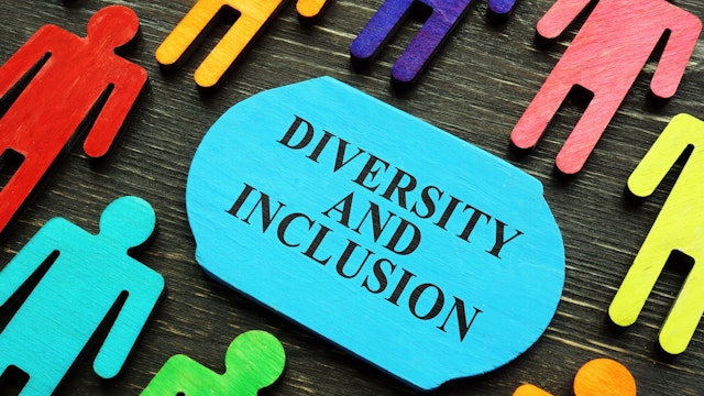 Diversity and inclusion phrase and colored wooden figurines.
