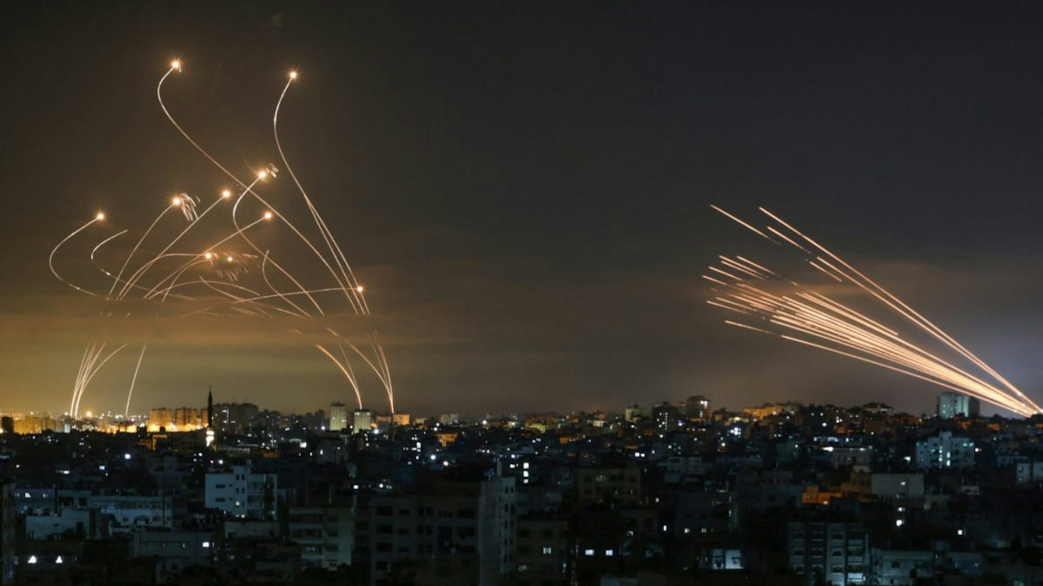 The Israeli Iron Dome missile defence system (L) intercepts rockets (R) fired by the Hamas movement towards southern Israel from Beit Lahia in the northern Gaza Strip as seen in the sky above the Gaza Strip overnight on May 14, 2021.