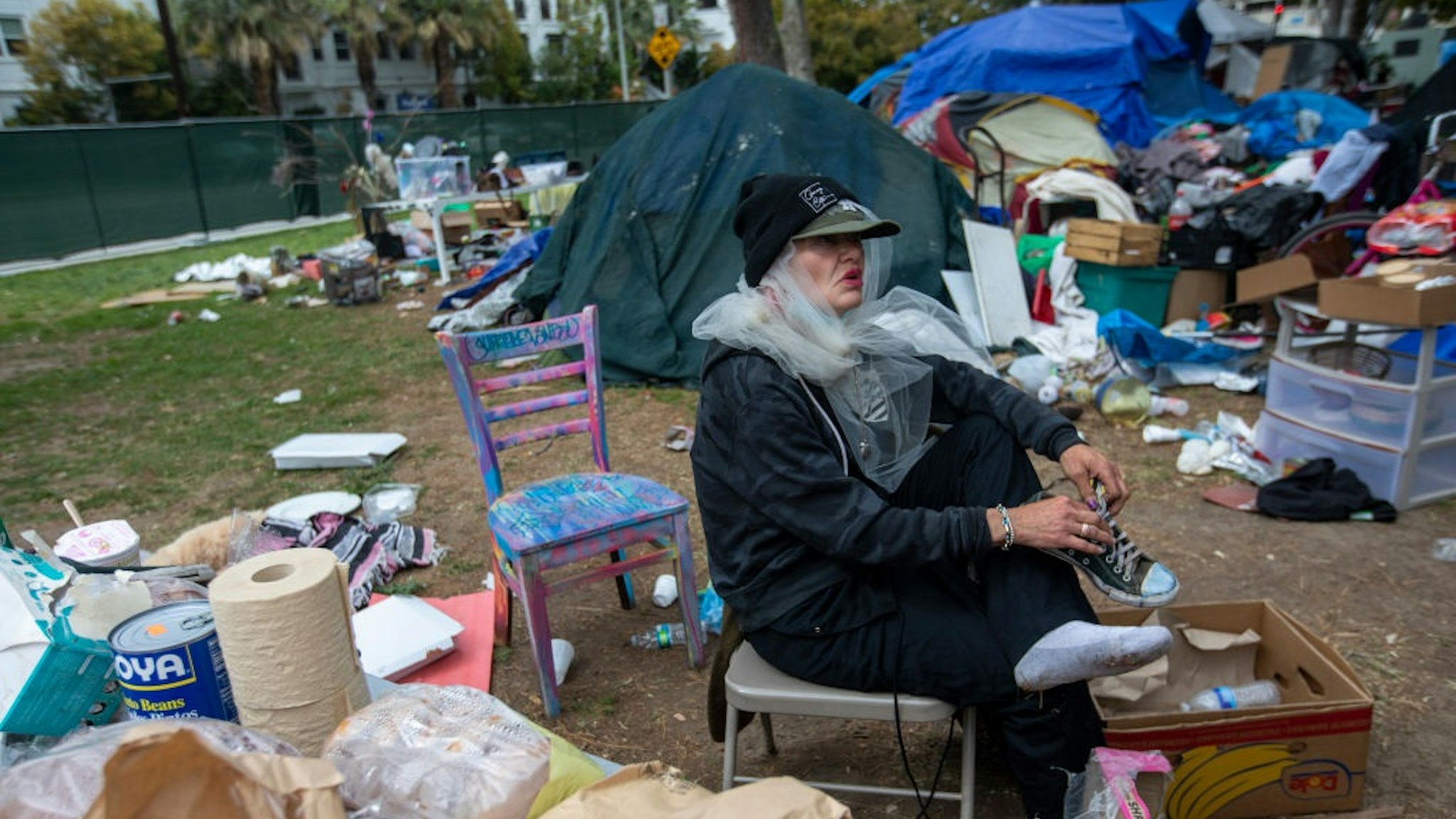LOS ANGELES, CA - MARCH 25: Still wearing her wedding vail Valerie Zeller puts on her shoes as she is packing outside her tent next other tents at Echo Park Lake Thursday, March 25, 2021 in Los Angeles, CA.