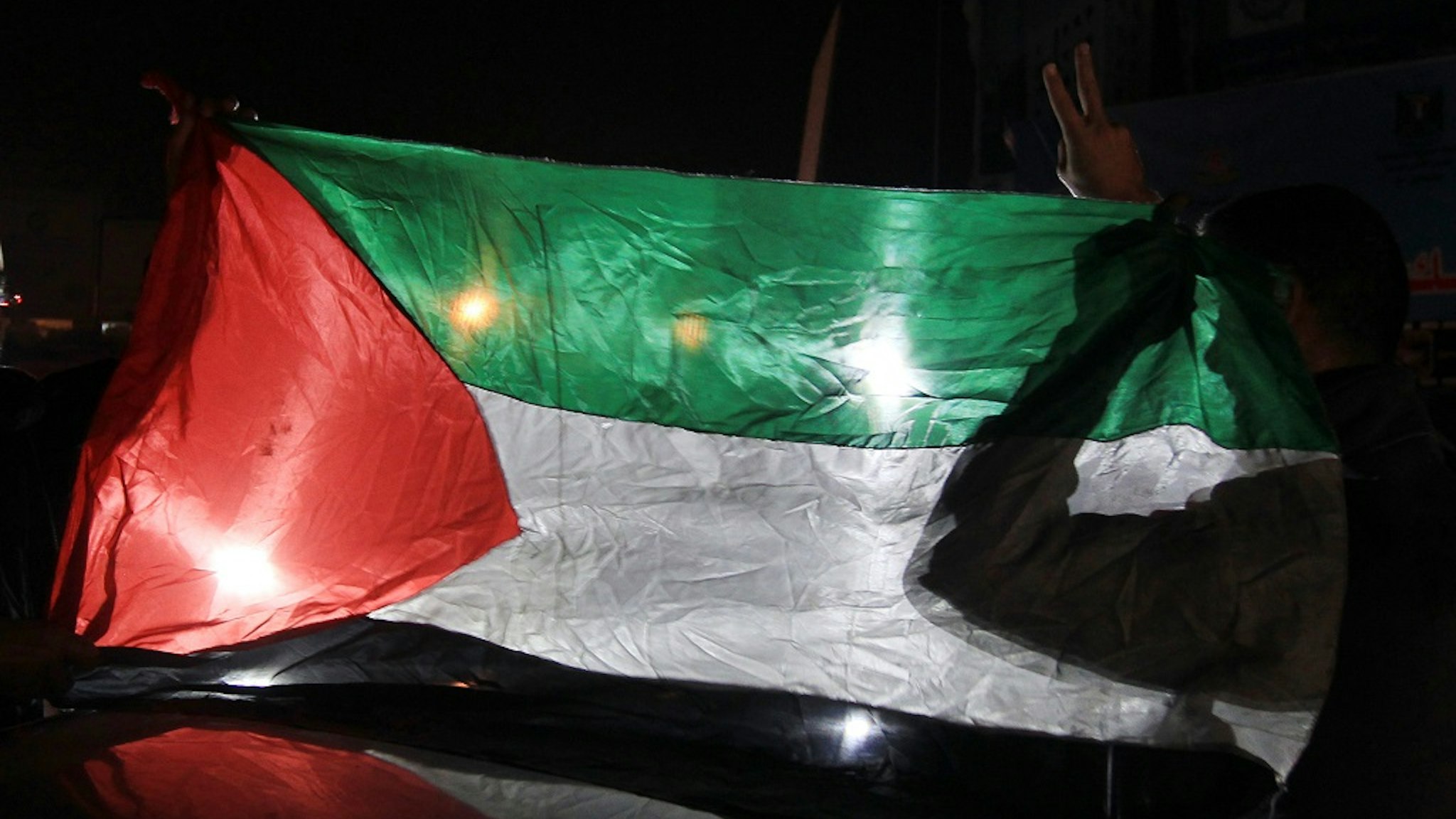 Palestinians hold up their national flag as they celebrate the beginning of the truce with Israel in Gaza City on November 21, 2012.