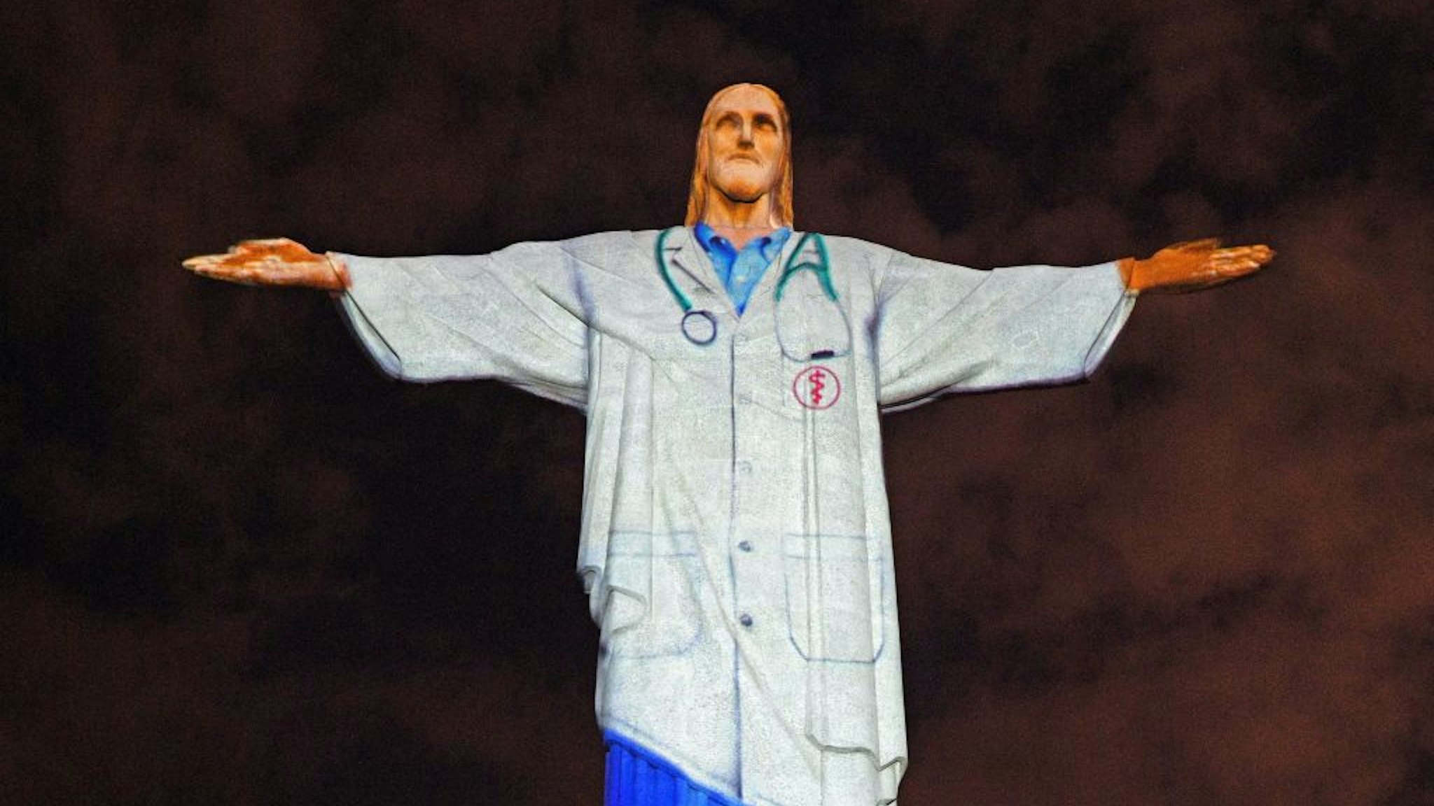 TOPSHOT - View of the world famous Christ the Redeemer statue on Easter day with a doctor's uniform projected on it in honour of all the medical staff fighting the COVID-19 coronavirus pandemic worldwide in Rio de Janeiro, Brazil on April 12, 2020.