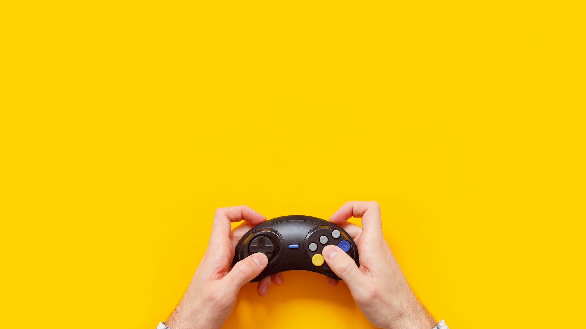 Cropped Hand Of Man Holding Joystick Over Yellow Background - stock photo