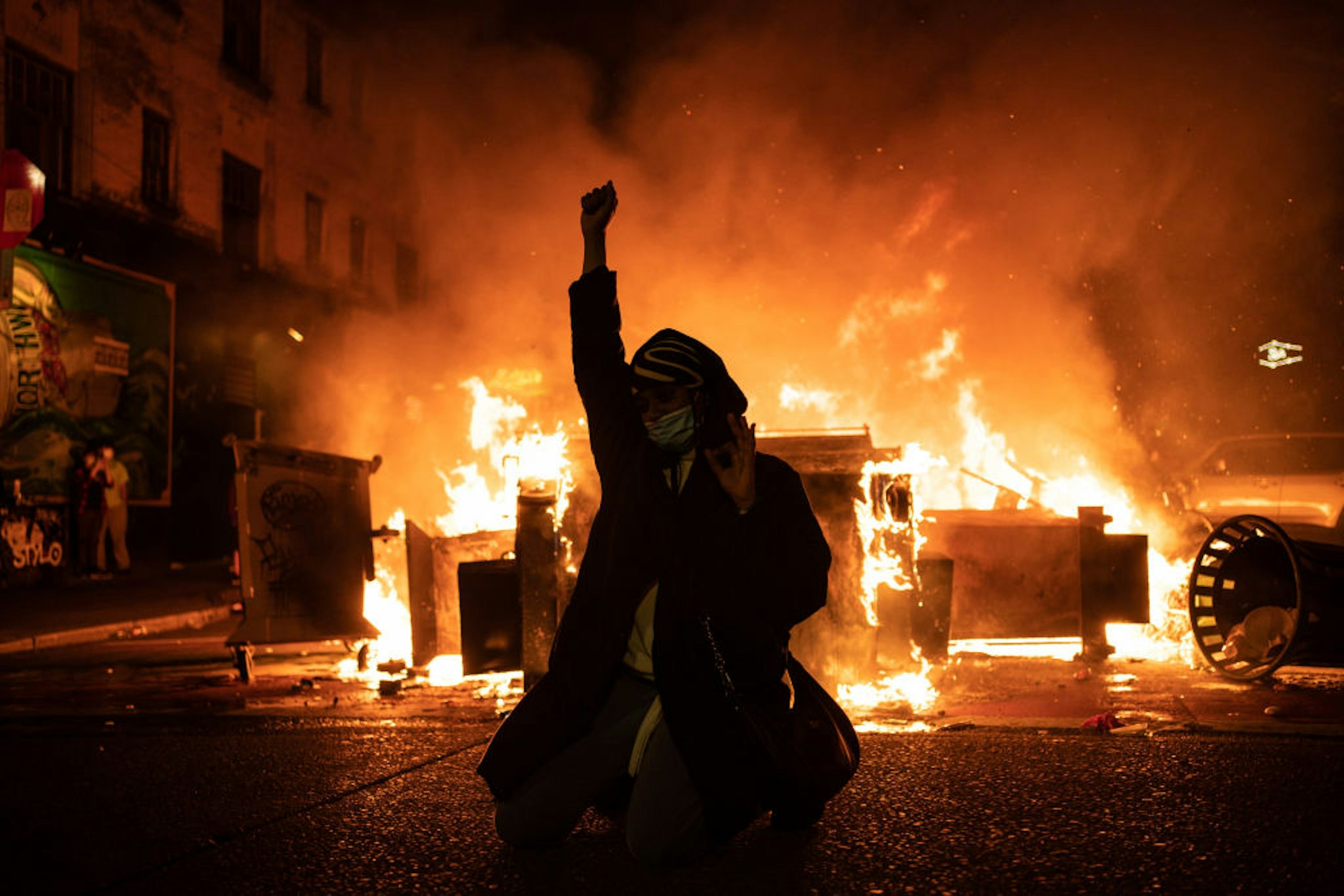 SEATTLE, WA - JUNE 08: A demonstrator raises their fist as a fire burns in the street after clashes with law enforcement near the Seattle Police Departments East Precinct shortly after midnight on June 8, 2020 in Seattle, Washington. Earlier in the evening, a suspect drove into the crowd of protesters and shot one person, which happened after a day of peaceful protests across the city. Later, police and protesters clashed violently during ongoing Black Lives Matter demonstrations following the death of George Floyd. (Photo by David Ryder/Getty Images)