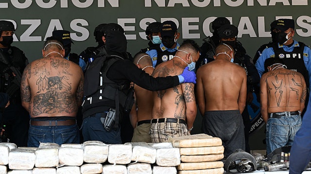 Members of the criminal gang Mara Salvatrucha (MS-13) are escorted by officers of the National Police in Tegucigalpa on February 19, 2021, after the dismantling of an operations centre of the organisation found in the mountains of the department of Olancho, north of Honduras.