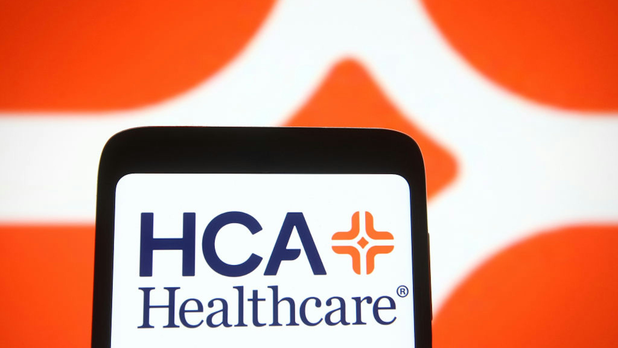 UKRAINE - 2021/04/23: In this photo illustration, the HCA Healthcare logo seen displayed on a smartphone and a pc screen.