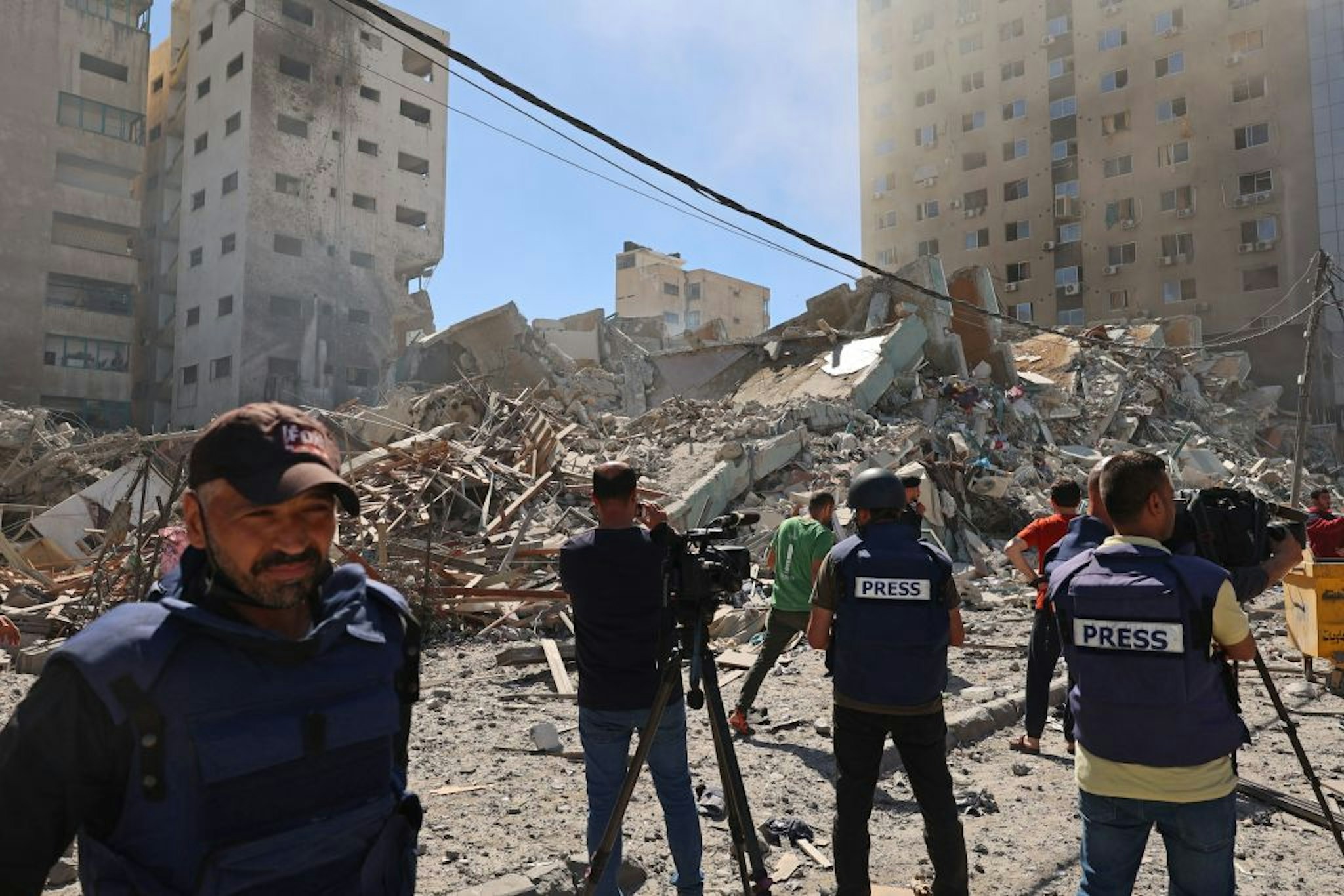 Palestinian journalists cover the destroyed Jala Tower, which was housing international press offices, following an Israeli airstrike in the Gaza Strip on May 15, 2021.