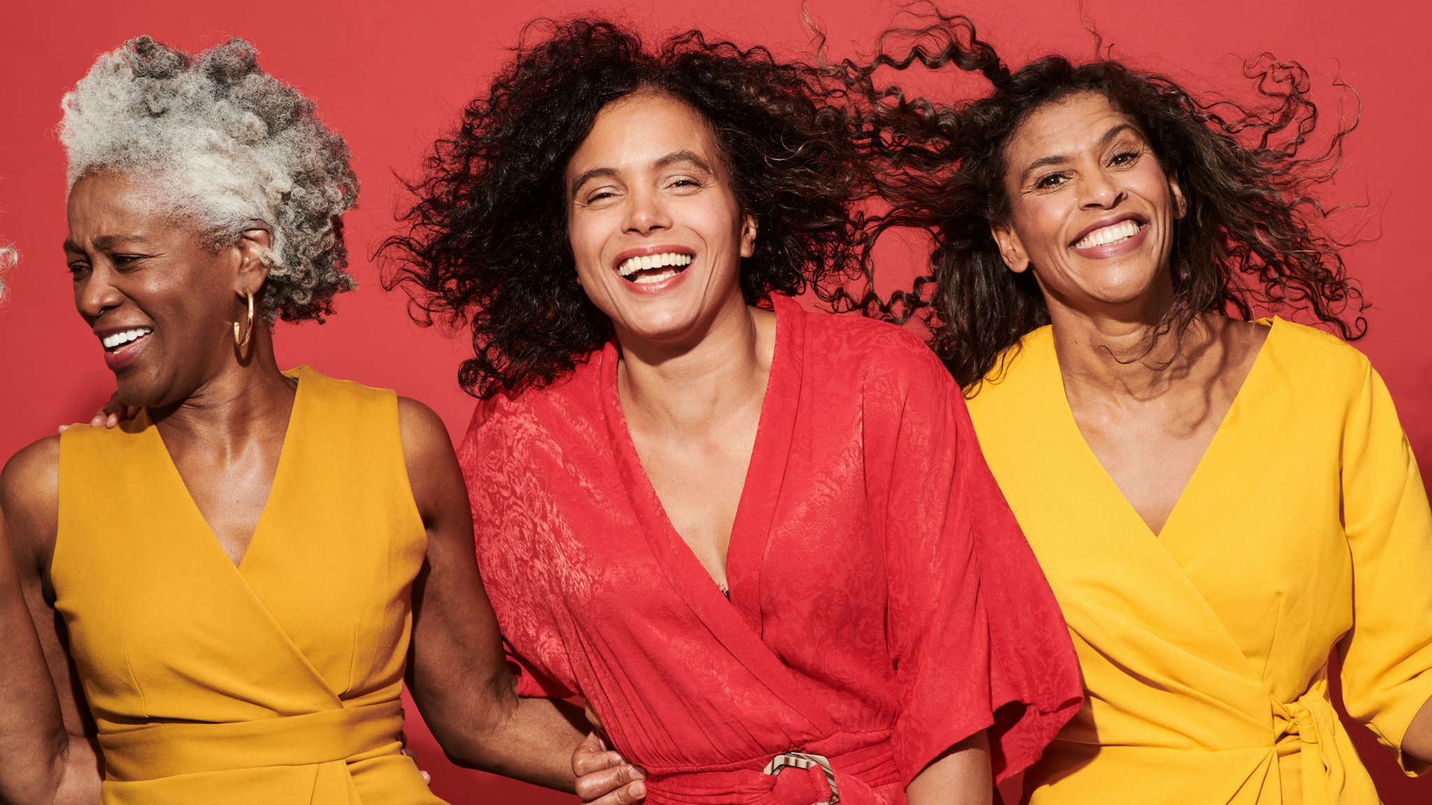 Portrait of a group of mature women against a red background.