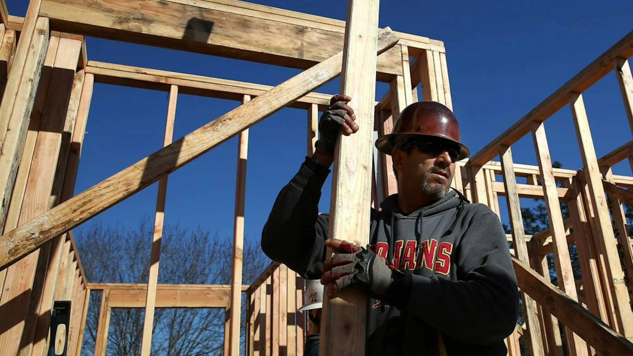 PETALUMA, CA - JANUARY 21: A worker carries lumber as he builds a new home on January 21, 2015 in Petaluma, California. According to a Commerce Department report, construction of new homes increased 4.4 percent in December, pushing building of new homes to the highest level in nine years.