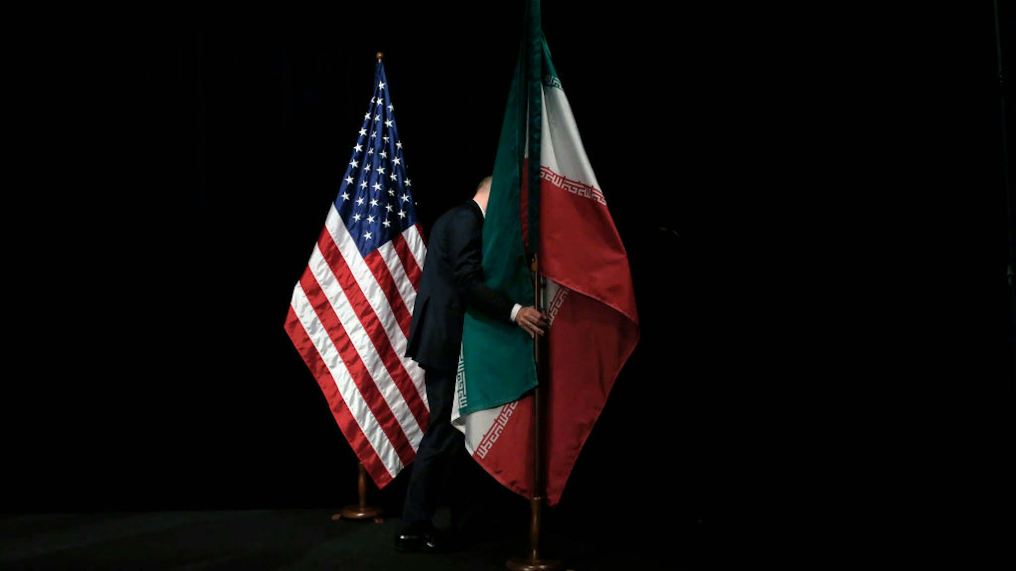 A staff removes the Iranian flag from the stage after a group picture with foreign ministers and representatives of Unites States, Iran, China, Russia, Britain, Germany, France and the European Union during the Iran nuclear talks at Austria International Centre in Vienna, Austria on July 14, 2015. Major powers clinched a historic deal aimed at ensuring Iran does not obtain the nuclear bomb, opening up Tehran's stricken economy and potentially ending decades of bad blood with the West.