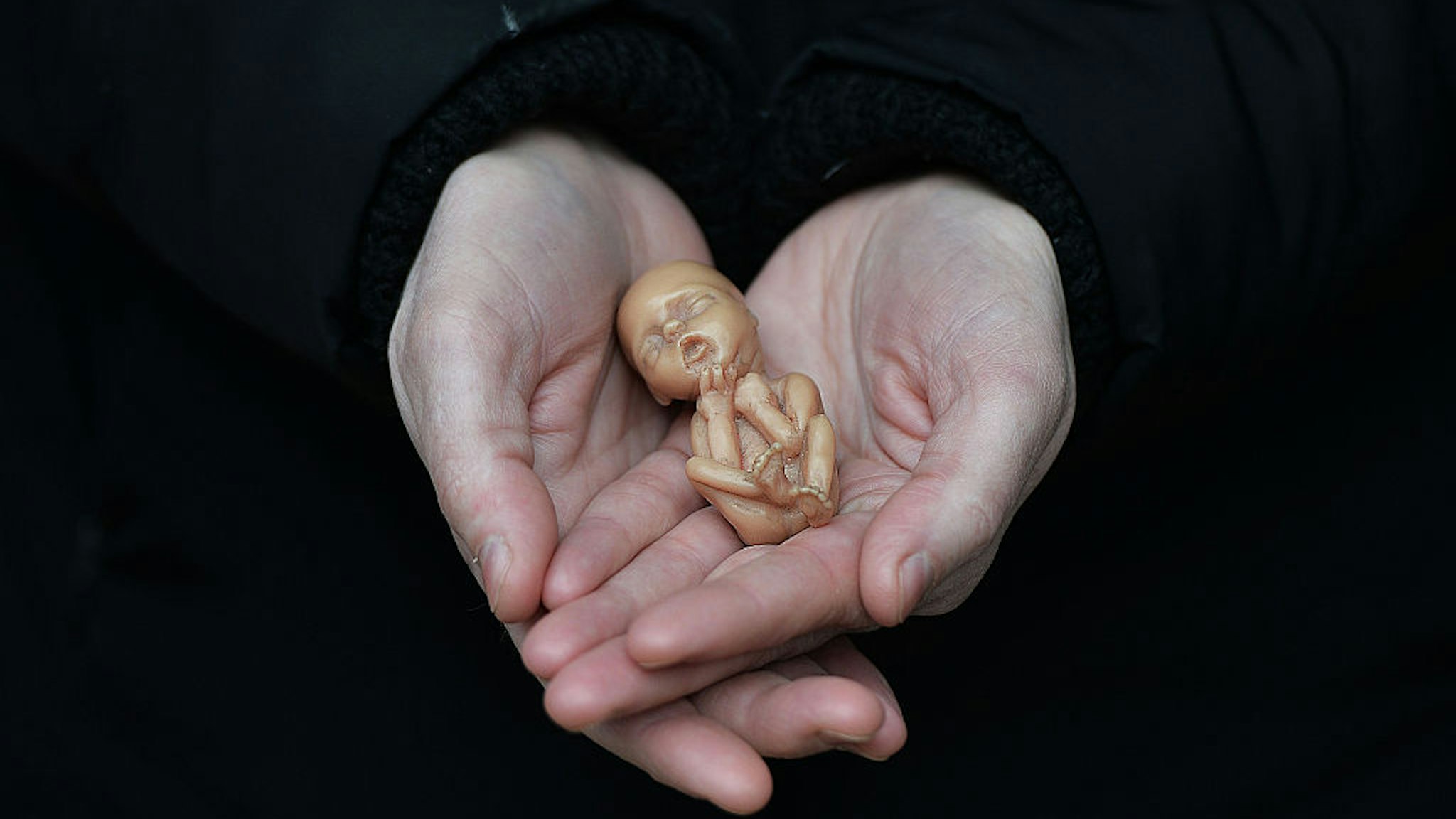 BELFAST, NORTHERN IRELAND - APRIL 07: A Pro Life campaigner displays a plastic doll representing a 12 week old foetus as she stands outside the Marie Stopes Clinic on April 7, 2016 in Belfast, Northern Ireland. The anit abortion supporters have protested outside the clinic where women can go for advice concerning terminating their pregnancy since it opened in 2012. The abortion laws in Northern Ireland are in the news again after a 21 year old Northern Irish woman was convicted and sentenced earlier this week for procuring a miscarriage. The woman who cannot be named for legal reasons had pleaded guilty to two charges of procuring her own abortion by using a poison and of supplying a poison with intent to procure a miscarriage, she was ten-twelve weeks pregnant at the time. She was given a three-month prison sentence by Judge David McFarland at Belfast high court, which was suspended for two years. Unlike the rest of the United Kingdom, the law in Northern Ireland rules that terminating a pregnancy is illegal except in very limited circumstances.