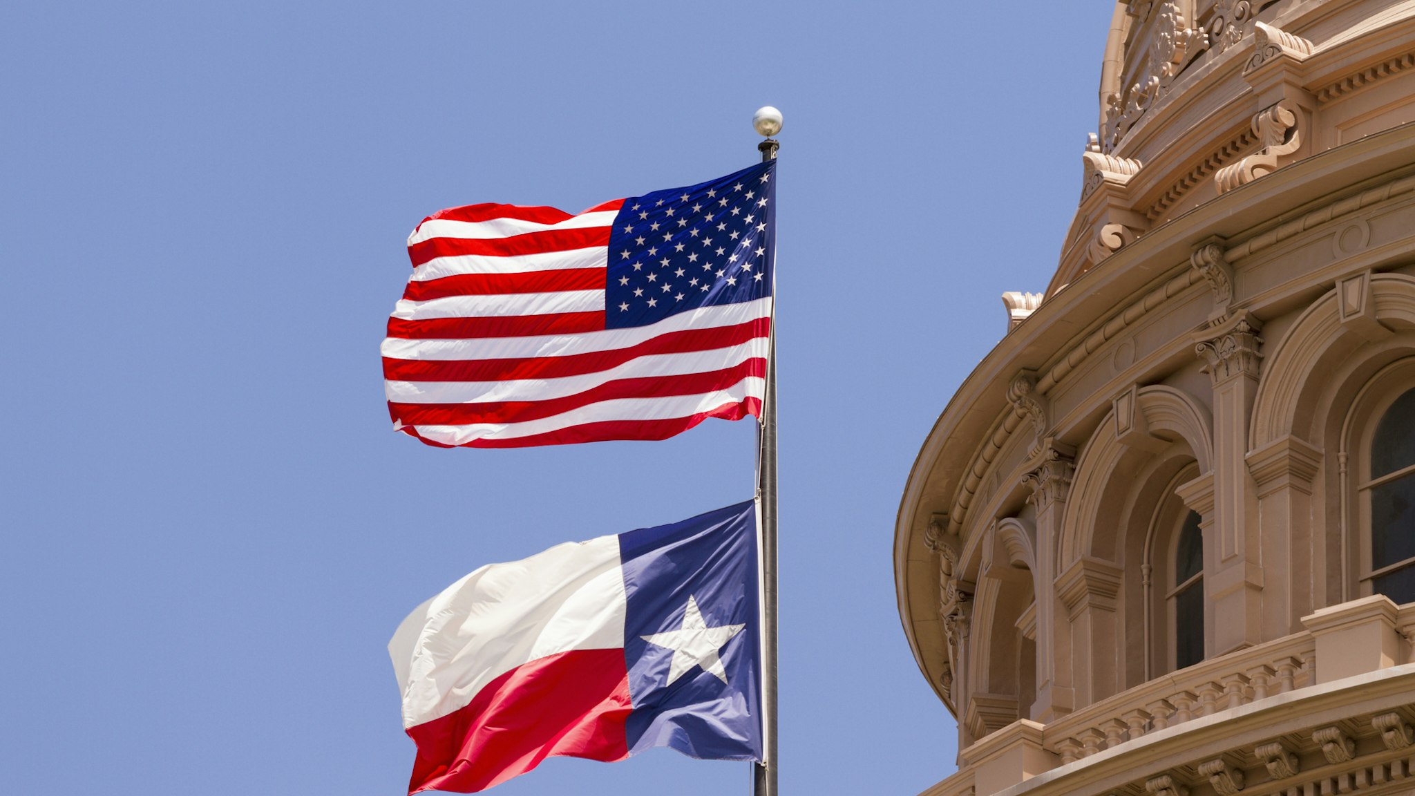 US and Texas flags flying over Texas State Capitol building, Austin, USA