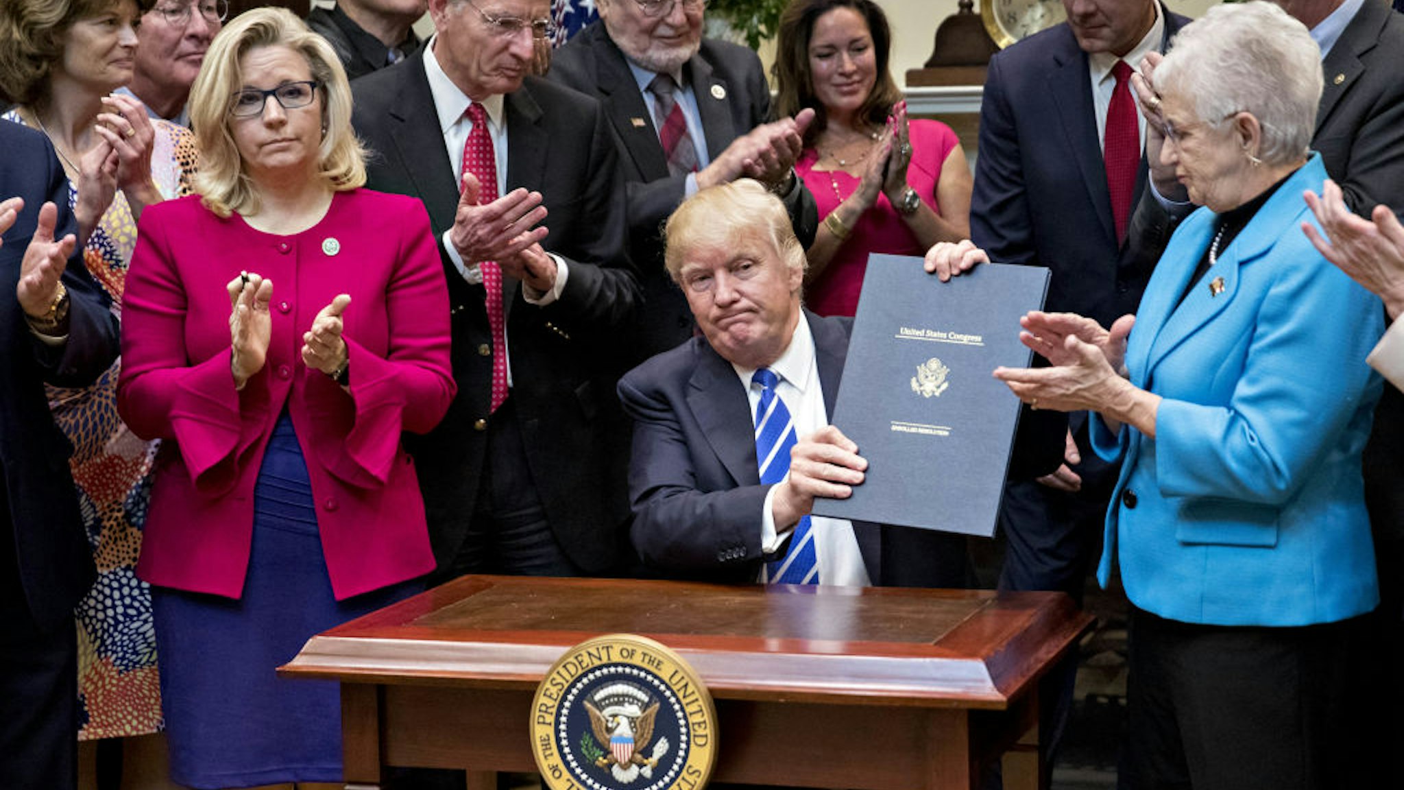 U.S. President Donald Trump holds up H.J. Res. 58, which overturns a rule requiring states to report specific information on teacher preparation programs, such as student learning outcomes, and rate their effectiveness, after signing the bill during a ceremony in the Roosevelt Room of the White House in Washington, D.C., U.S., on Monday, March 27, 2017. Trump signed four bills, H.J. Res 37, H.J. Res 44, H.J. Res. 57 and H.J. Res. 58, that nullify measures put in place during former President Obama's administration.