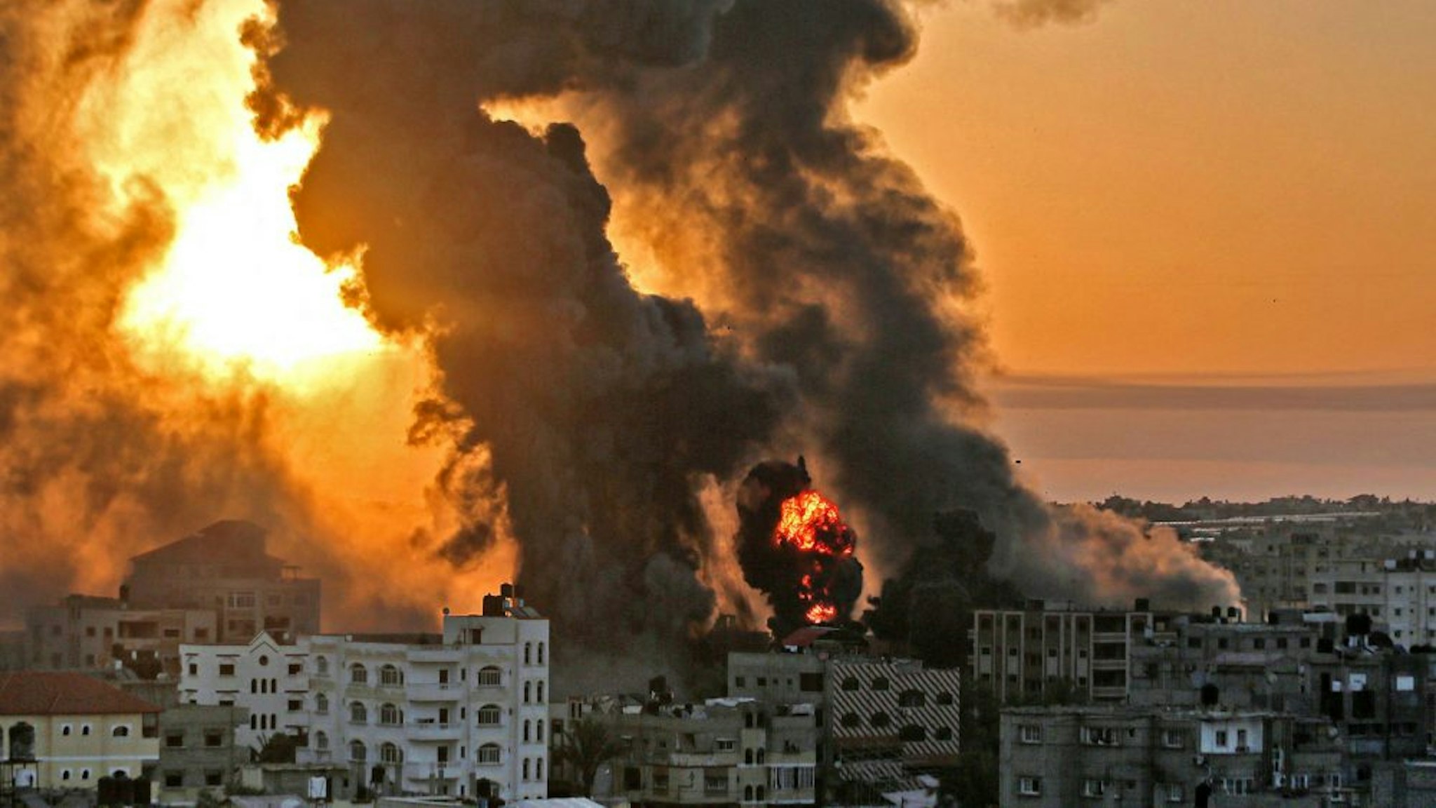 TOPSHOT - A fire rages at sunrise in Khan Yunish following an Israeli airstrike on targets in the southern Gaza strip, early on May 12, 2021. - Israeli air raids in the Gaza Strip have hit the homes of high-ranking members of the Hamas militant group, the military said Wednesday, with the territory's police headquarters also targeted.