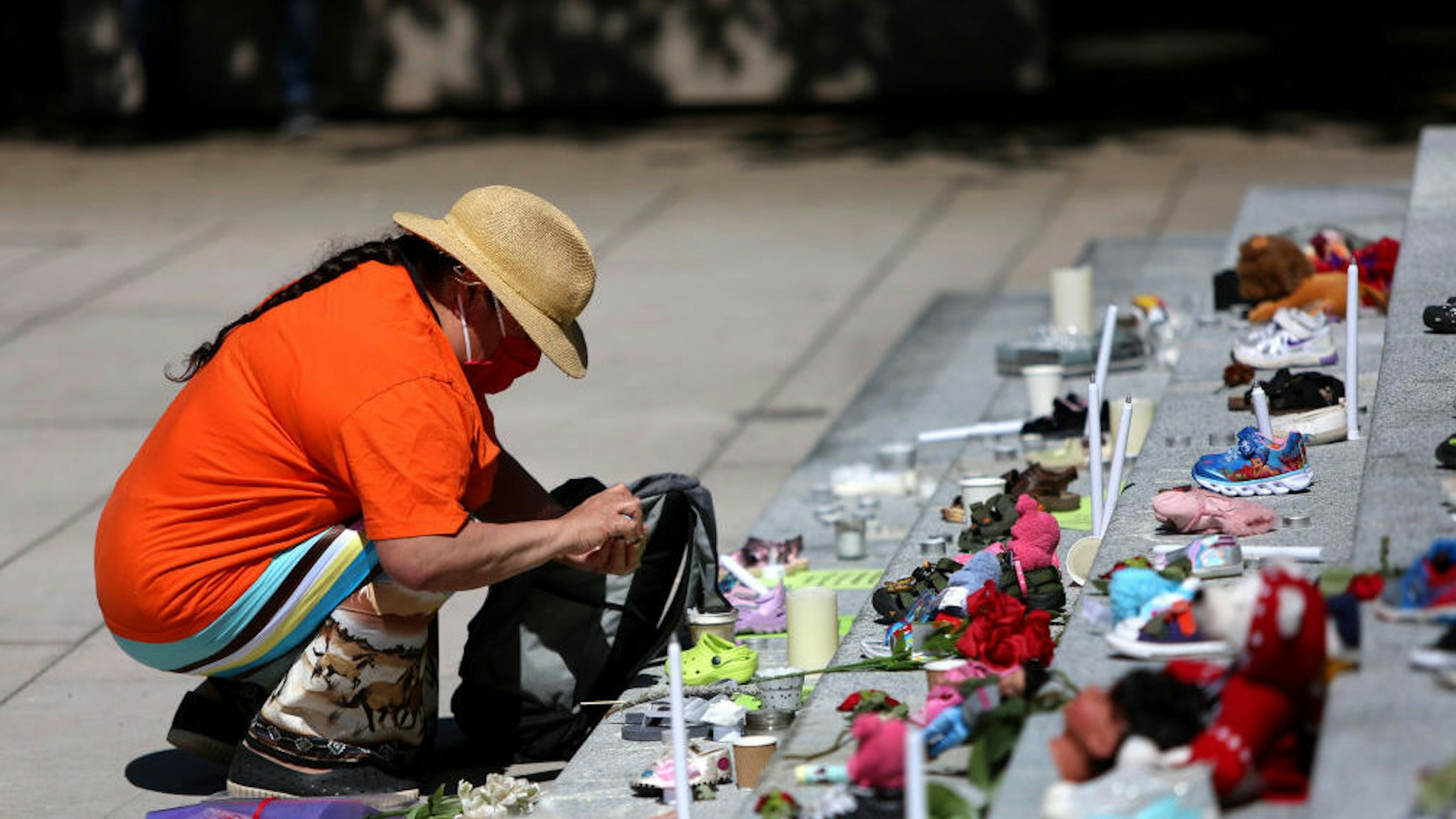 VANCOUVER, CANADA - MAY 29 : A woman mourns over 215 pairs of kids shoes outside Vancouver Art Gallery during a memorial on May 29, 2021 in Vancouver, British Columbia, Canada The remains of 215 children have been found buried at a Canadian residential school, an Indigenous band confirmed Thursday.