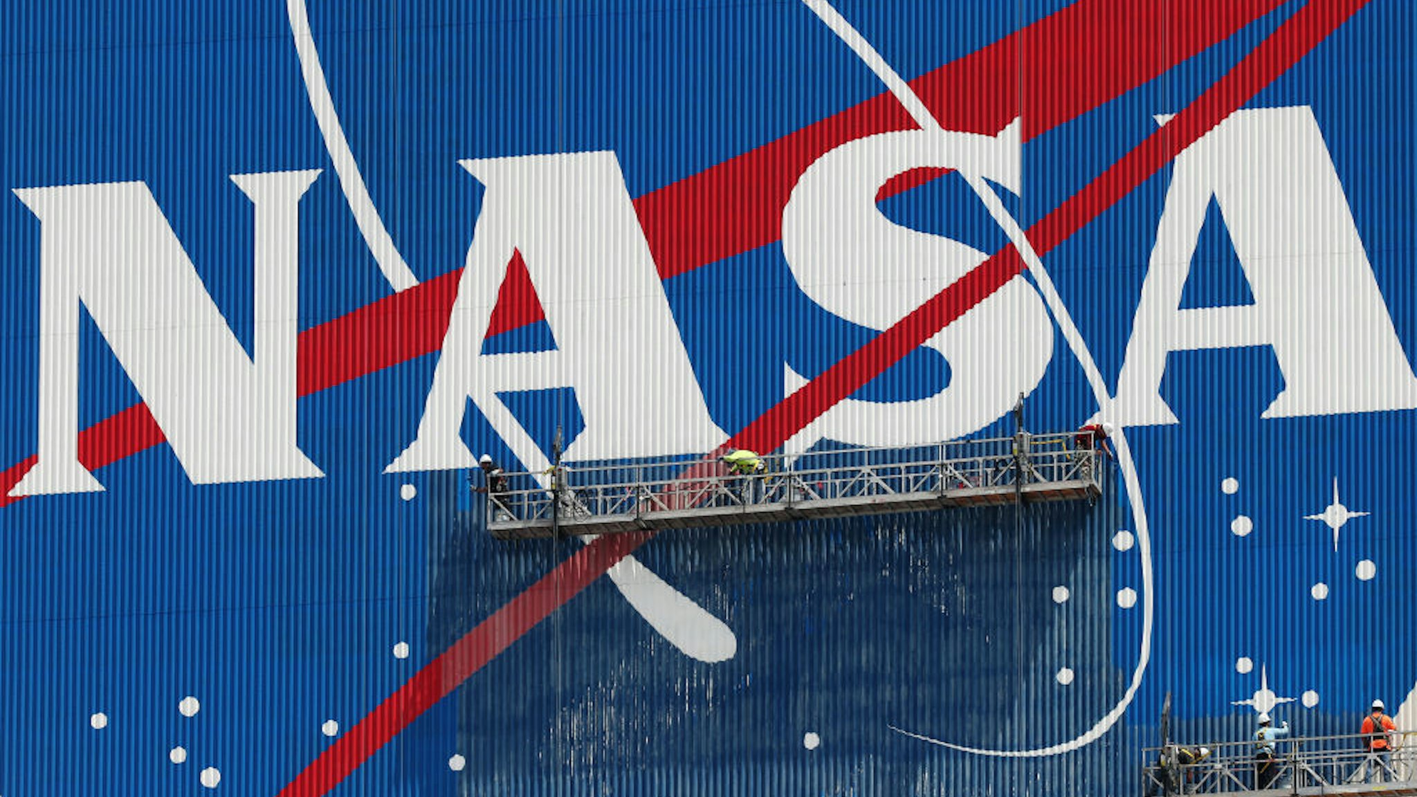 CAPE CANAVERAL, FLORIDA - MAY 28: Workers repaint the NASA logo on the Vehicle Assembly Building at the Kennedy Space Center on May 28, 2020 in Cape Canaveral, Florida. SpaceX’s Crew Dragon spacecraft will try to launch again on Saturday after weather scrubbed yesterday's attempt. It will be the first manned mission since the end of the Space Shuttle program in 2011 to be launched into space from the United States. (Photo by Joe Raedle/Getty Images)