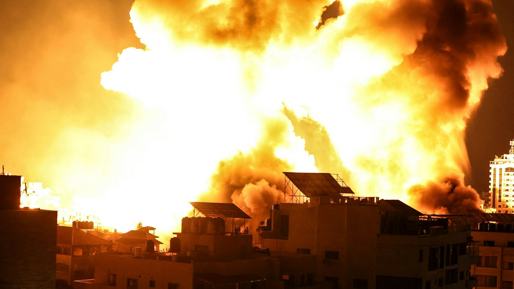 A ball of fire explodes above buildings in Gaza City as Israeli forces shell the Palestinian enclave, early on May 18, 2021. - Israeli jets kept up a barrage of air strikes against the Palestinian enclave of Gaza as a week of violence that has killed more than 200 people pushed world leaders to step up mediation.