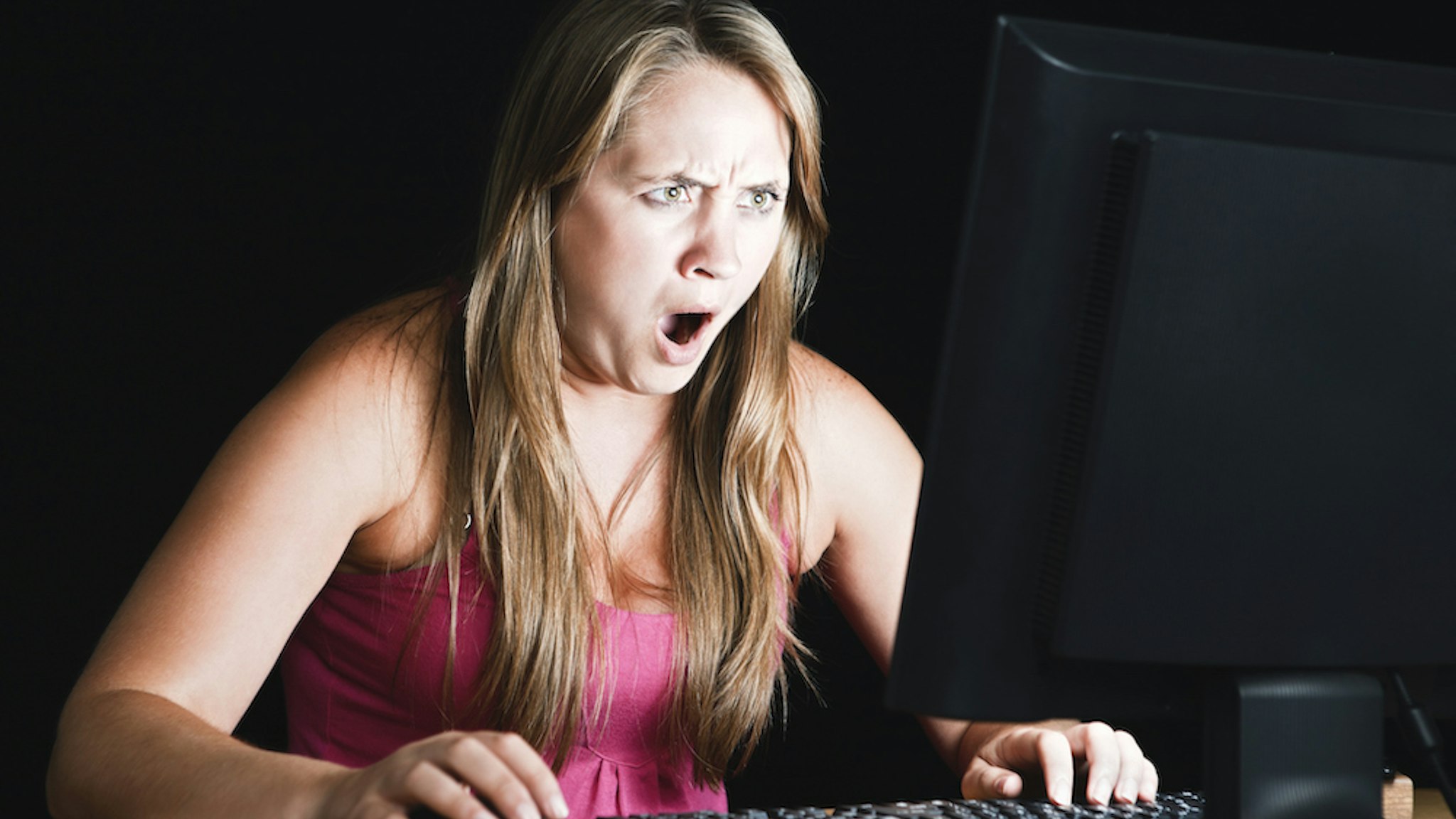 Shocked woman stares at computer screen. (RapidEye via Getty Images)