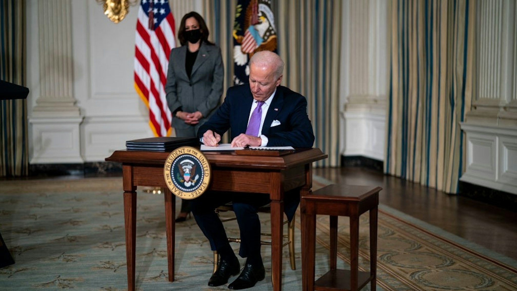 WASHINGTON, DC - JANUARY 26: (L-R) Vice President Kamala Harris looks on as U.S. President Joe Biden signs executives orders related to his racial equity agenda in the State Dining Room of the White House on January 26, 2021 in Washington, DC. President Biden signed executive actions Tuesday on housing and justice reforms, including a directive to the Department of Justice to end its use of private prisons. (Photo by