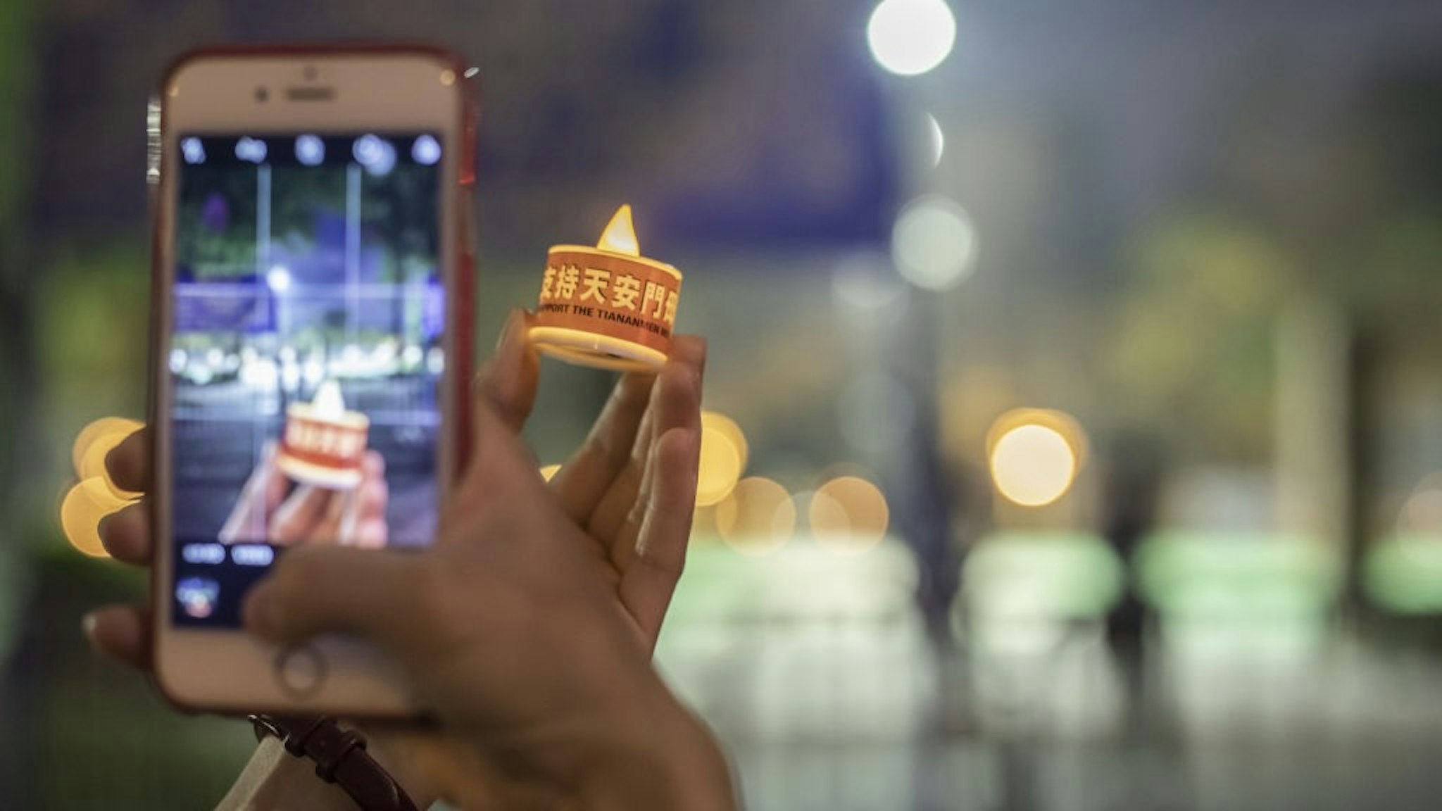 Hong Kong Police Bans Annual Tiananmen Vigil For The Second Straight Year A person takes a photo of an electronic candle outside Victoria Park, the traditional site of the annual Tiananmen candlelight vigil, in Hong Kong, China, on Friday, June 4, 2021. Hong Kong police on Friday warned democracy activists trying to commemorate Chinas deadly Tiananmen Square crackdown in 1989 that they could be violating the sweeping national security law imposed by China. Photographer: Paul Yeung/Bloomberg via Getty Images Bloomberg / Contributor via Getty Images