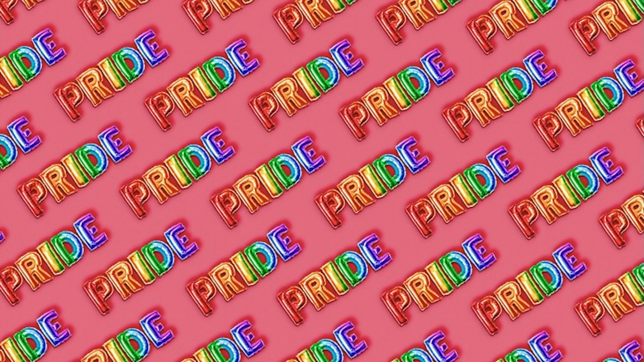 Gay PRIDE on pink - stock photo PRIDE gay text in rainbow letters balloons on pink background.Top view. retales botijero via Getty Images