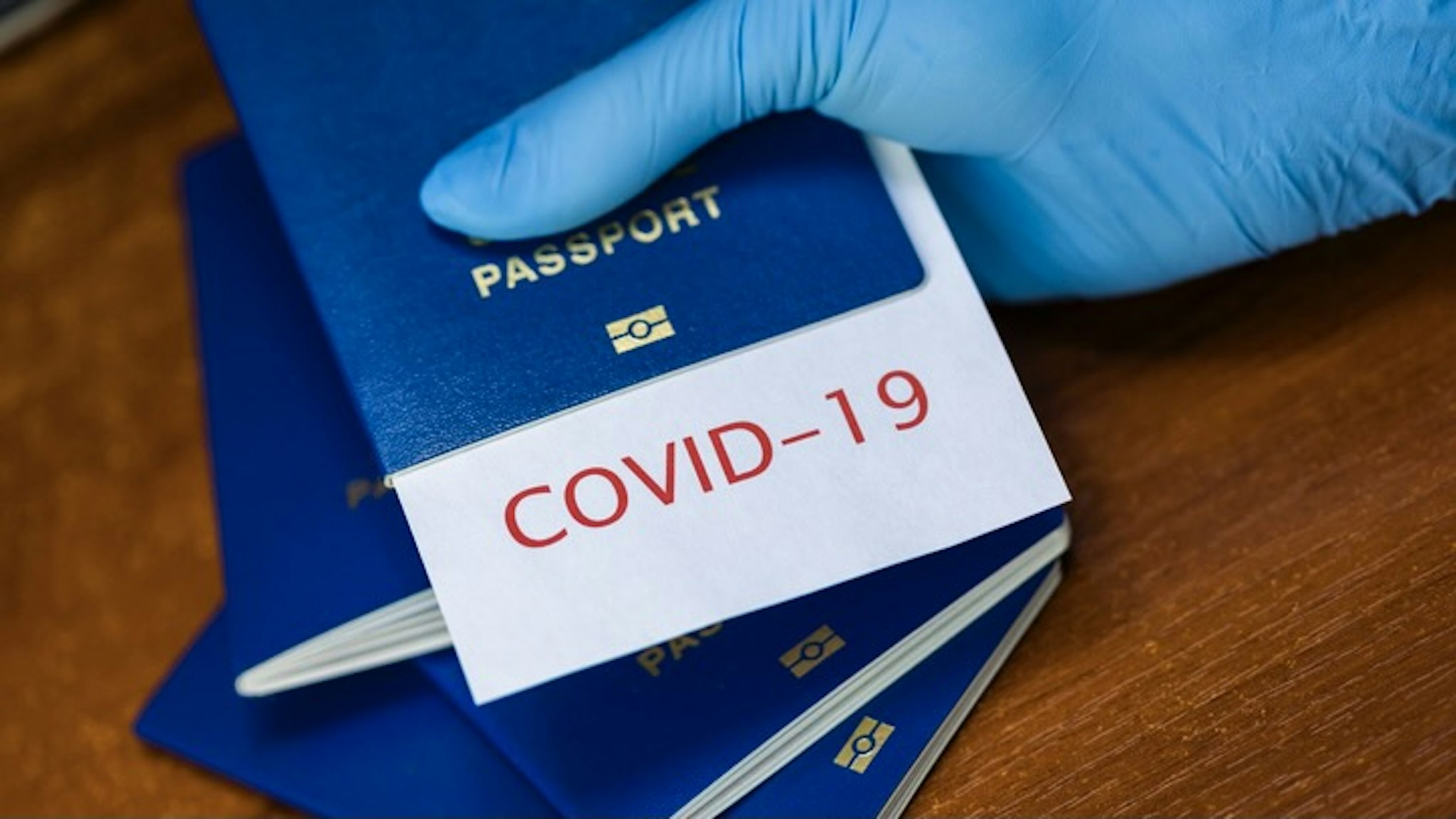 Immunity passport or risk-free certificate concept. Traveling After the Coronavirus Pandemic - stock photo Man holding a passport with COVID-19 sign stamped onto a white paper, immunity passport or risk-free certificate concept, recovered Coronavirus COVID19 patients being issued proof of convalescence Anton Petrus via Getty Images