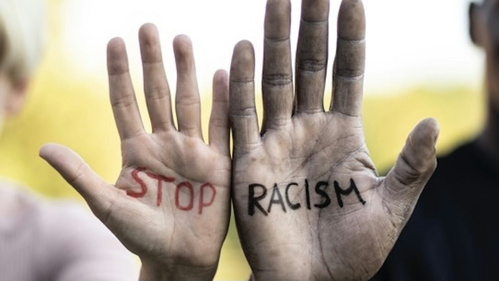 "Stop racism" concept, written on the hands of two multiethnic friends - stock photo Multiethnic friends holding their hands with written slogan "Stop racism" Vladimir Vladimirov via Getty Images