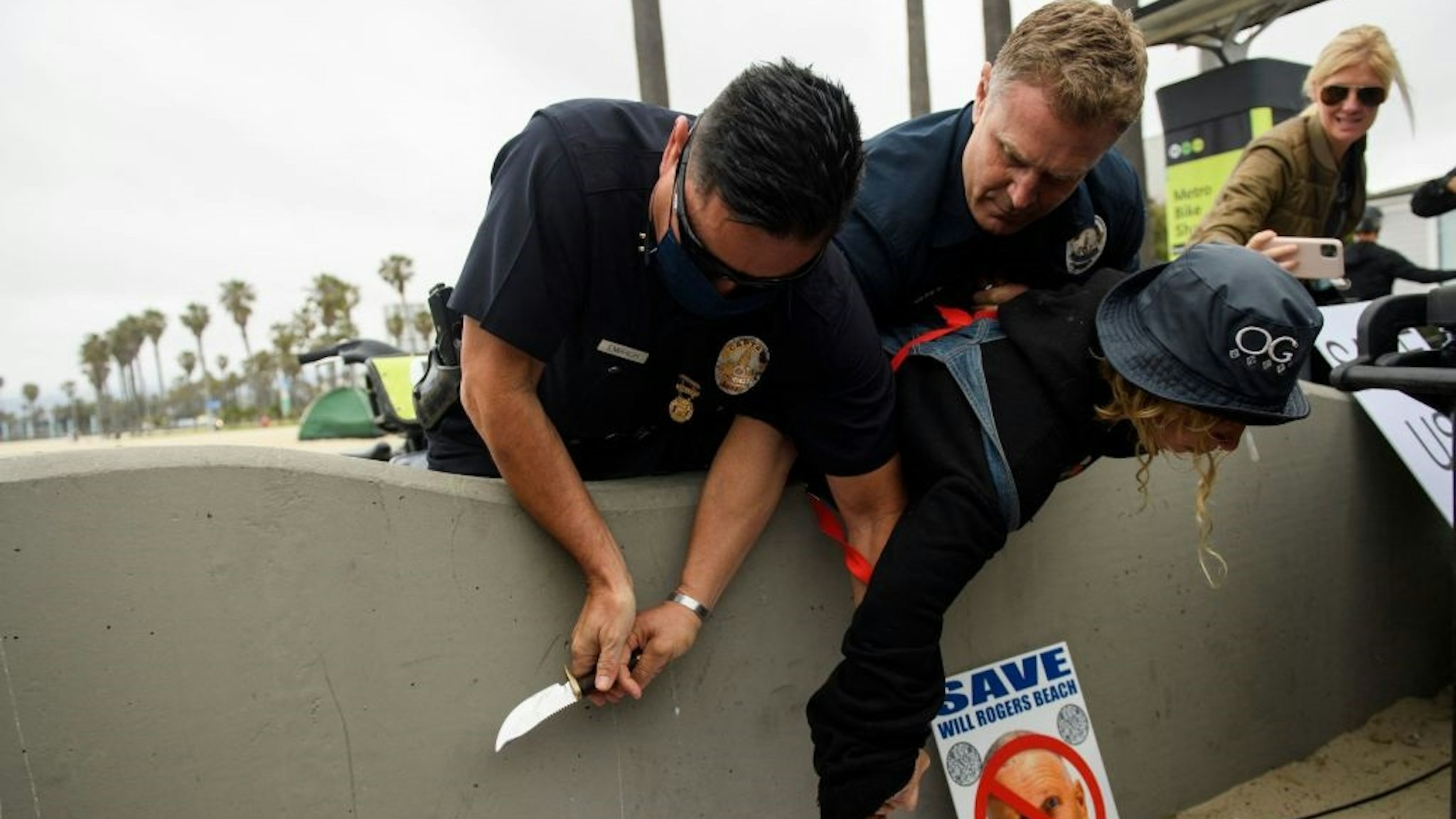 Los Angeles Police Department (LAPD) offices wrestle a knife away from a person experiencing homelessness as they were detained during an event with Los Angeles City Council Member and mayoral candidate Joe Buscaino announcing his "Plan For A Safer Los Angeles" at Venice Beach on June 7, 2021 in Los Angeles, California.