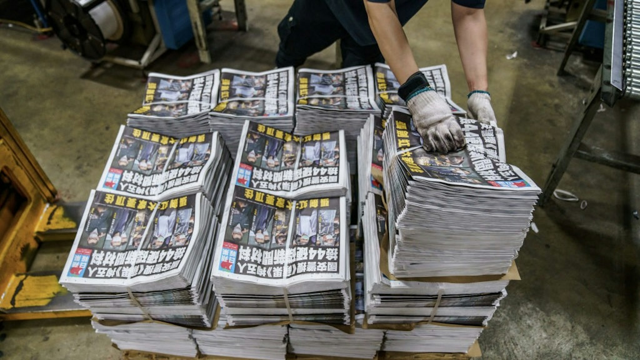 Printing of the Apple Daily Following Police Arrest of Top Editors Citing Security Law An employee arranges bundles of the Apple Daily newspaper, published by Next Digital Ltd., at the company's printing facility in Hong Kong, China, early on Friday, June 18, 2021. China took another step toward extinguishing any form of dissent in Hong Kong, hailing police in the city for arresting top editors of the pro-democracy Apple Daily and warning journalists not to write articles that challenge Beijing. Photographer: Lam Yik/Bloomberg via Getty Images Bloomberg / Contributor via Getty Images