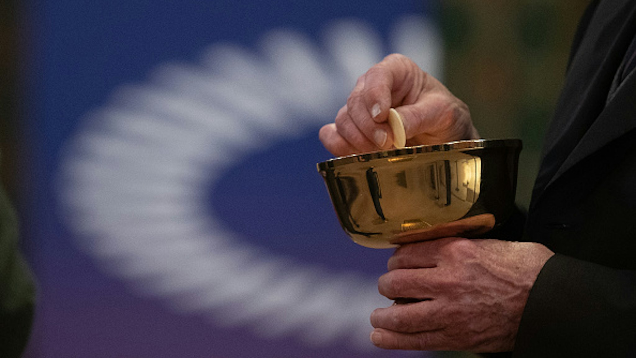 15 May 2021, Hessen, Frankfurt/Main: A member of the church congregation holds a wafer in his hand in front of the logo of the ÖKT during a service with communion in the Catholic Cathedral of St. Bartholomew. The service is being held as part of the 3rd Ecumenical Church Day. Four services will be held simultaneously in the city, all under the motto "Celebrating the Eucharist in an ecumenically sensitive way". Photo: Sebastian Gollnow/dpa