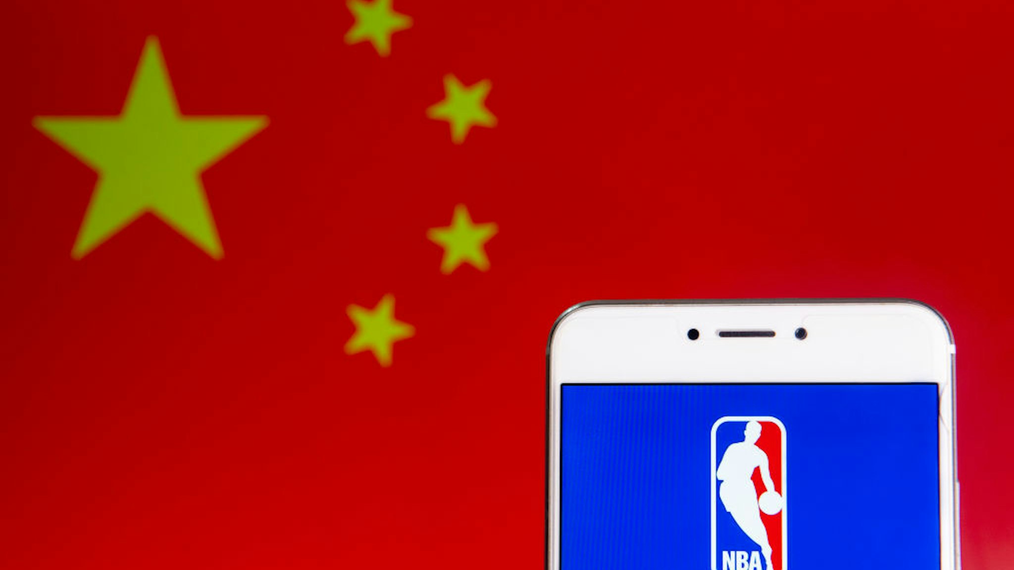 In this photo illustration a American National Basketball Association (NBA) men's professional basketball league logo is seen on an Android mobile device with People's Republic of China flag in the background.