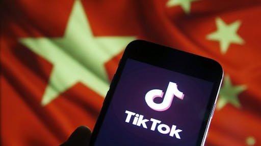 TikTok PARIS, FRANCE - DECEMBER 26: In this photo illustration the logo of Chinese media app for creating and sharing short videos, TikTok, also known as Douyin is displayed on the screen of a smartphone in front of a Chinese flag on December 26, 2019 in Paris, France. The social media app TikTok developed by Chinese company ByteDance continues its meteoric rise and exceeded the milestone of 1.5 billion downloads. Tik Tok now surpasses Facebook and Instagram.