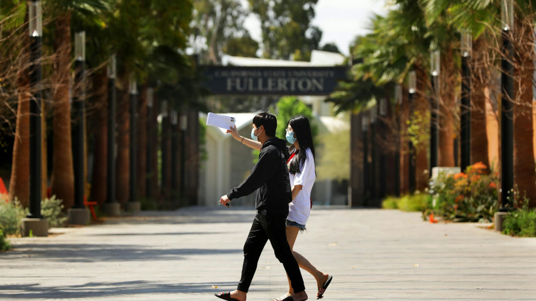 Cal State University Fullerton student Linh Trinh, 21, right, and her boyfriend Tan Nguyen, 21, walk around a deserted CSUF campus on Tuesday, April 21, 2020.