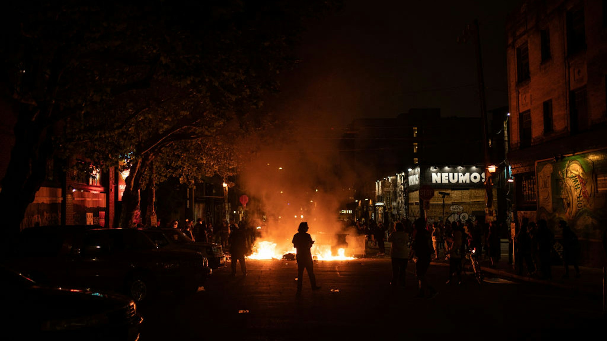 A demonstrator watches a fire burn in the street after clashing with law enforcement near the Seattle Police Departments East Precinct shortly after midnight on June 8, 2020 in Seattle, Washington.